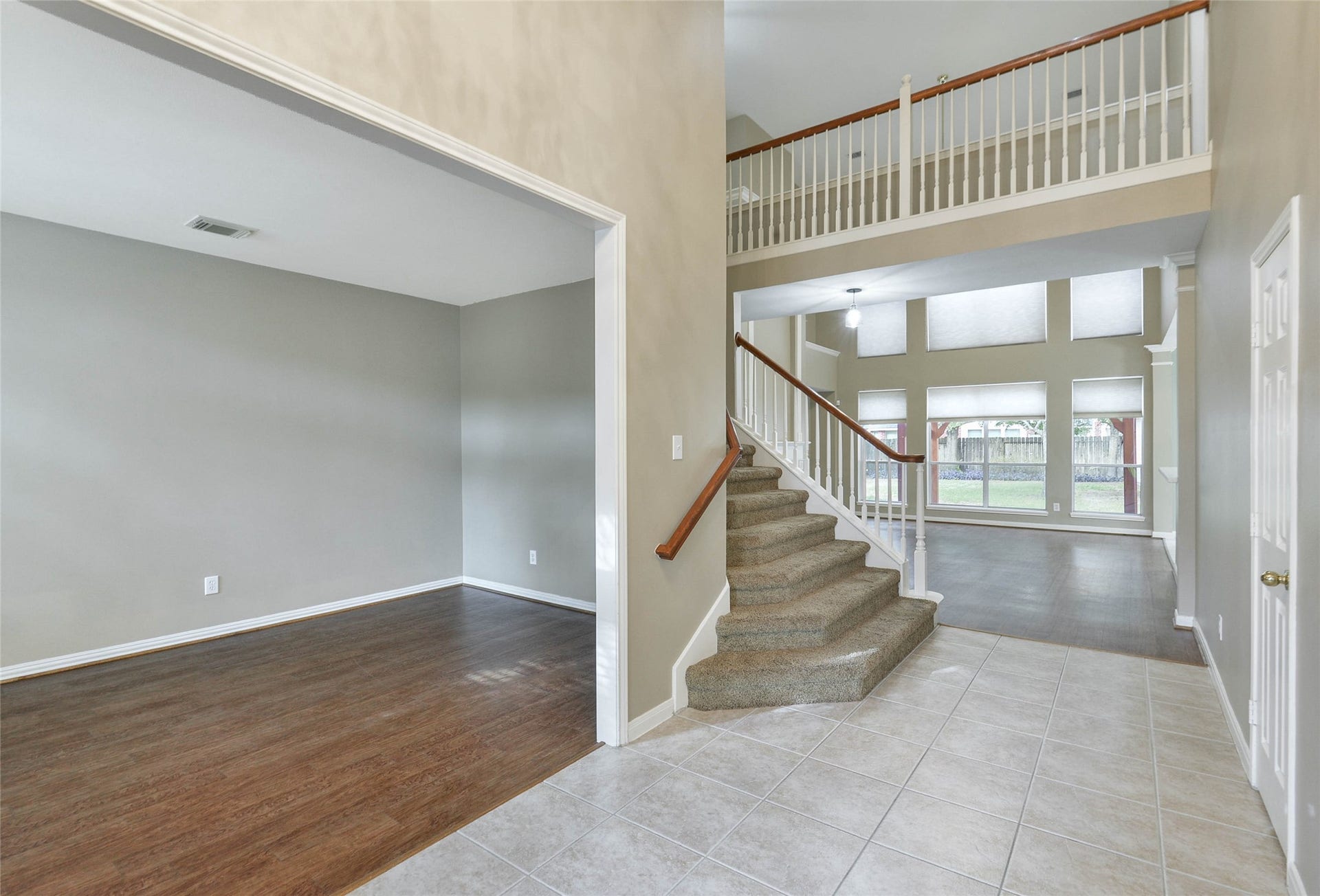 7023 Timber Edge Lane Lane, Humble, TX 77346 Spacious entryway with elegant staircase, high ceilings, and abundant natural light from large windows, leading to an open living area.