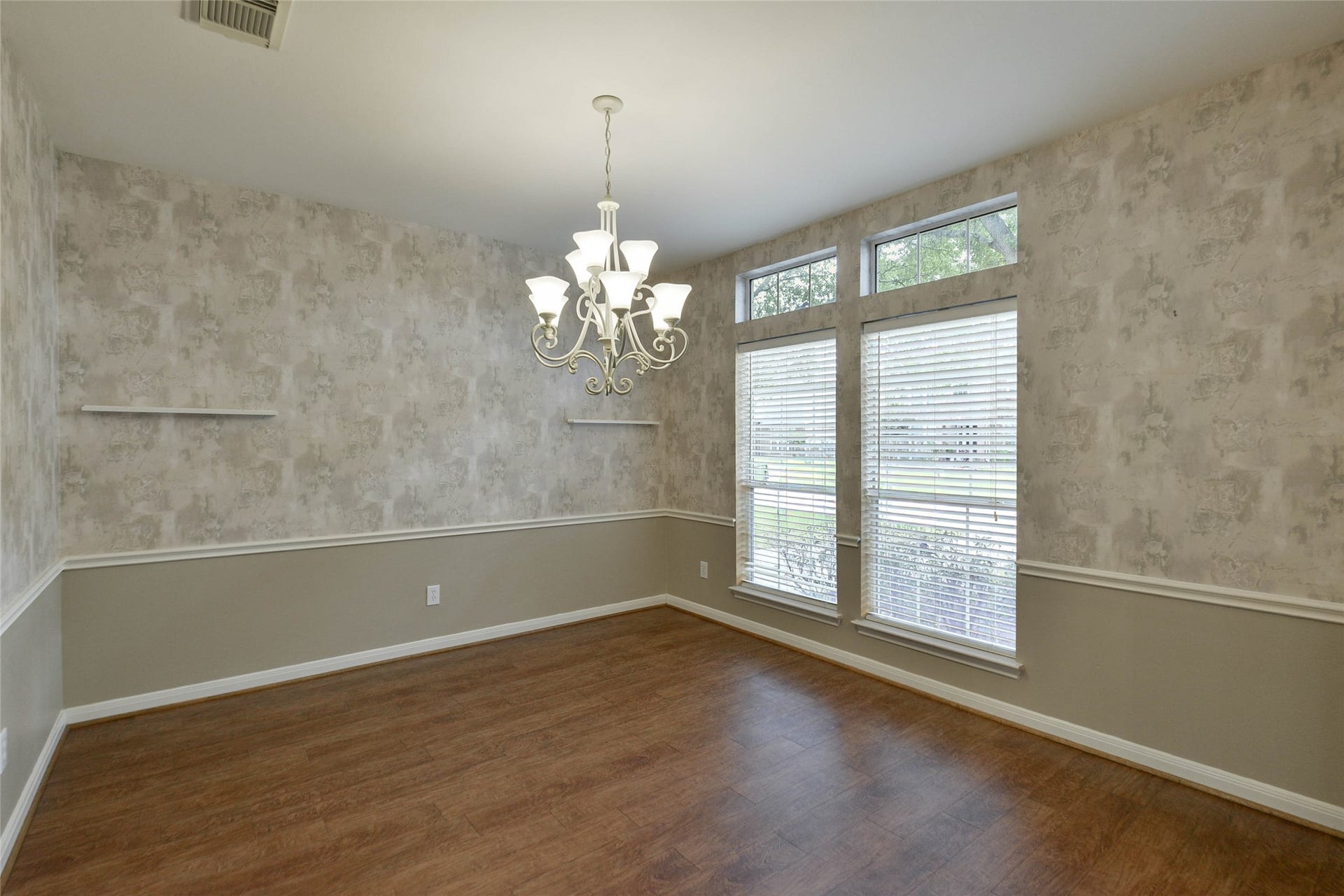 7023 Timber Edge Lane Lane, Humble, TX 77346 Charming dining room featuring elegant wood flooring, textured walls, and a stylish chandelier. Abundant natural light pours in through large windows, creating an inviting atmosphere.