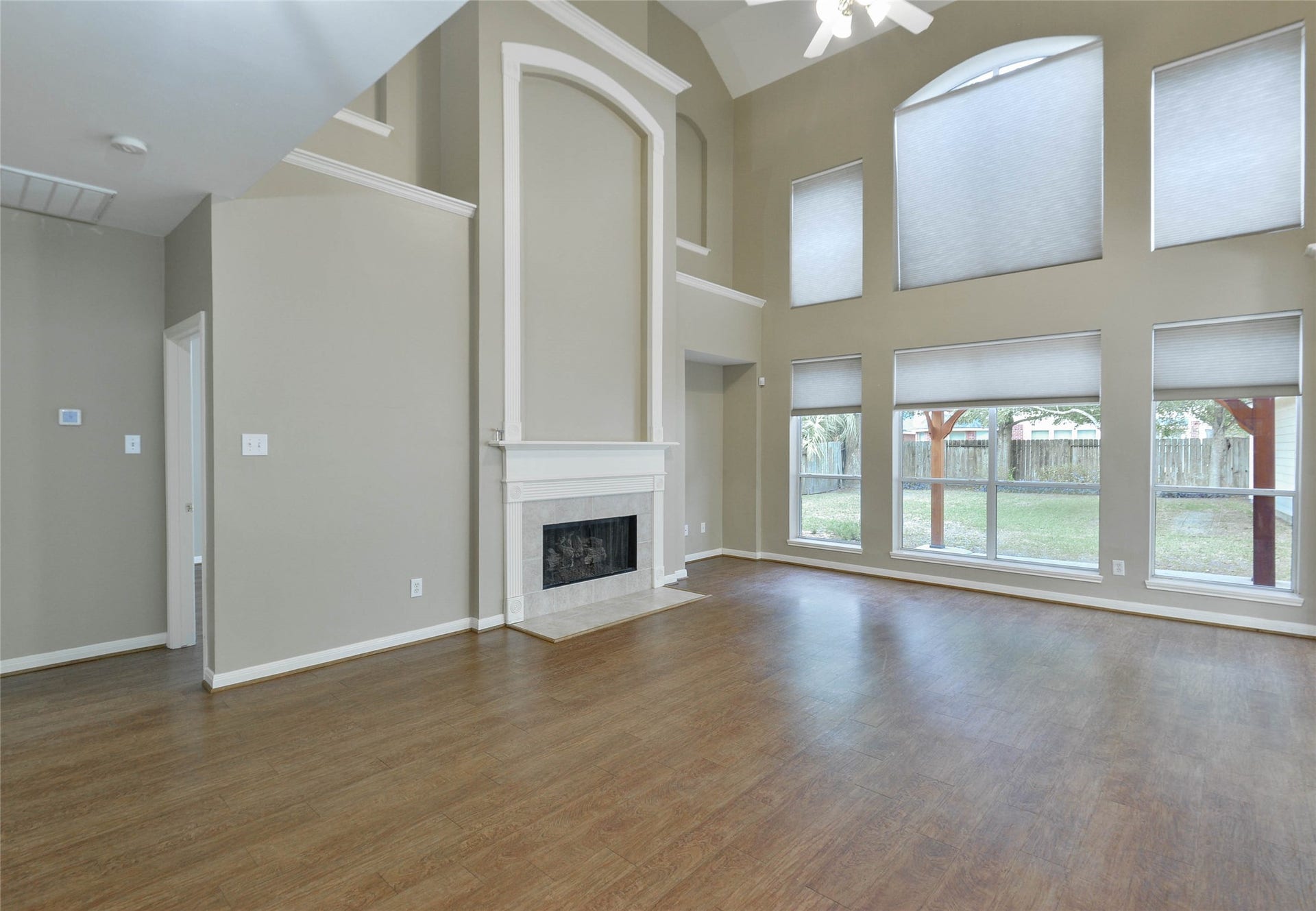 7023 Timber Edge Lane Lane, Humble, TX 77346 Spacious living room with soaring high ceilings and expansive windows, featuring a central fireplace and elegant wood flooring.