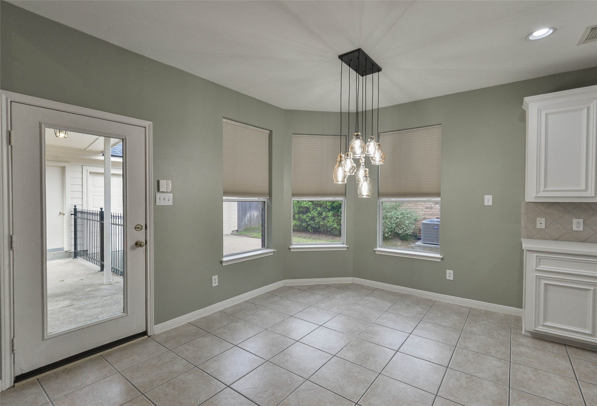 7023 Timber Edge Lane Lane, Humble, TX 77346 Breakfast nook with elegant pendant lighting, large windows offering garden views, and access to the patio through a glass door.