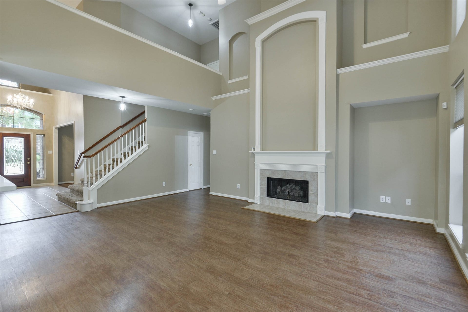 7023 Timber Edge Lane Lane, Humble, TX 77346 Living area with high ceilings, elegant fireplace, and an open layout leading to a grand staircase and entryway.