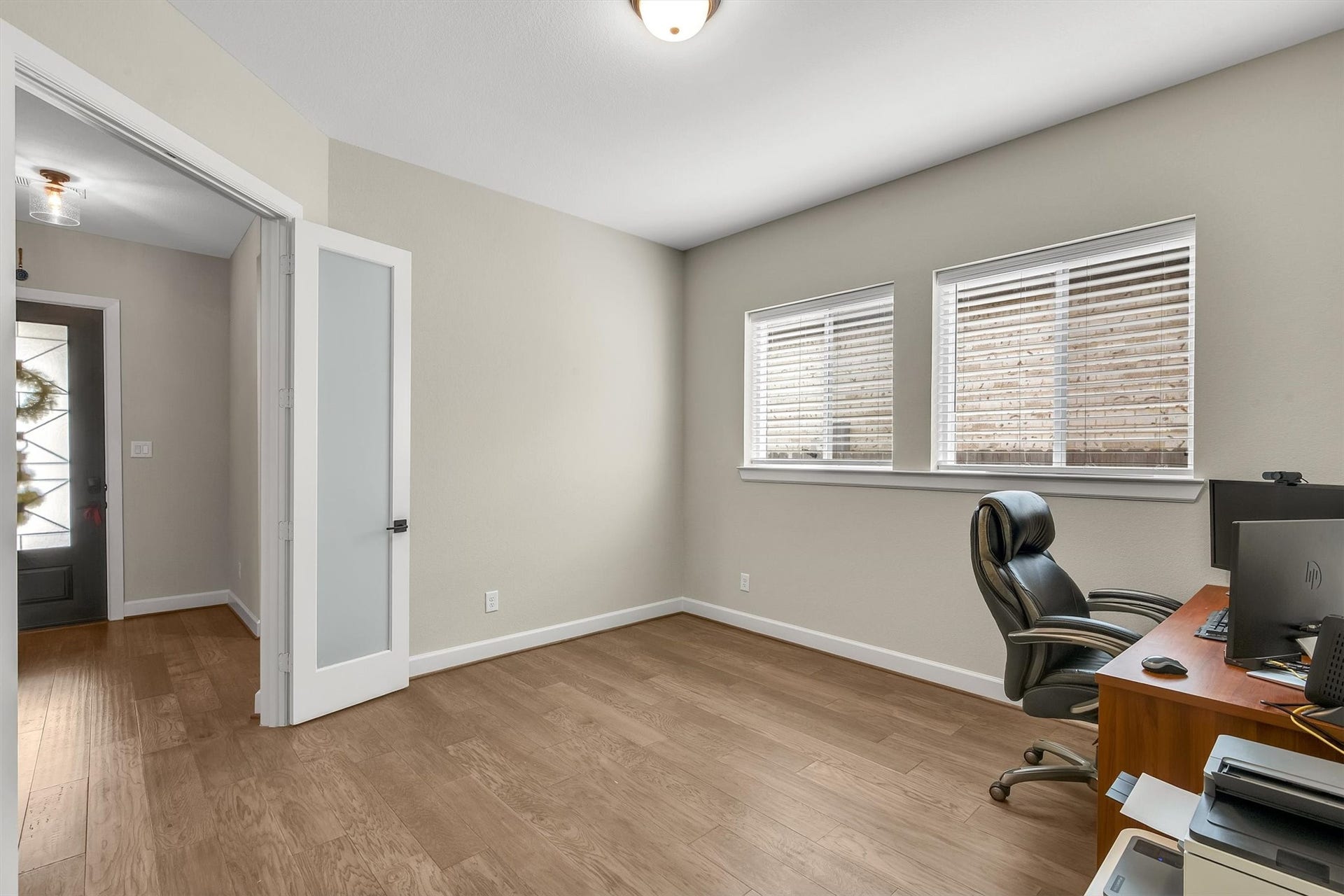 Bright, modern home office with hardwood flooring and double glass doors allows great privacy.