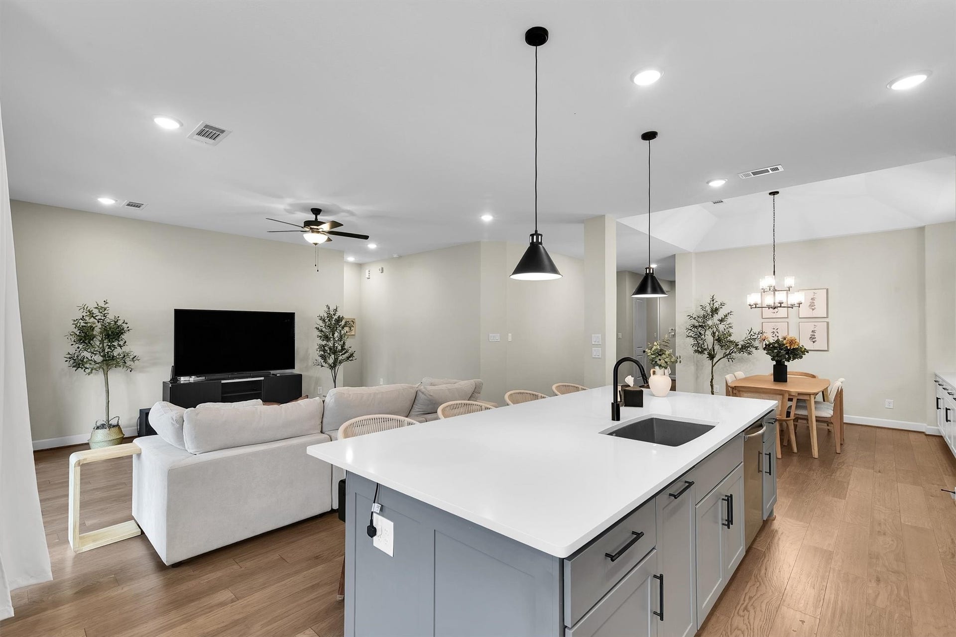 Modern open-concept living space and a spacious kitchen with a large island, stylish pendant lighting, and a cozy living area with a ceiling fan.