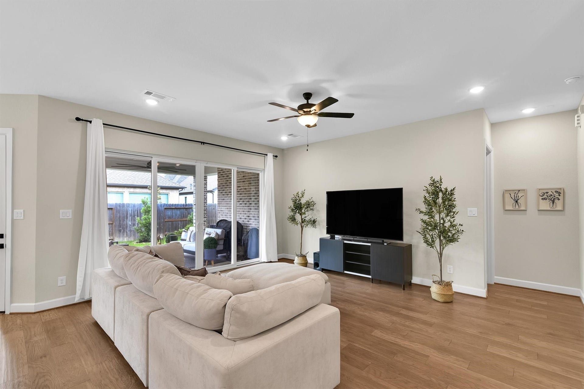 Sliding glass doors open to a patio, providing natural light and outdoor access. The room is enhanced with recessed lighting, a ceiling fan, and tasteful decor.