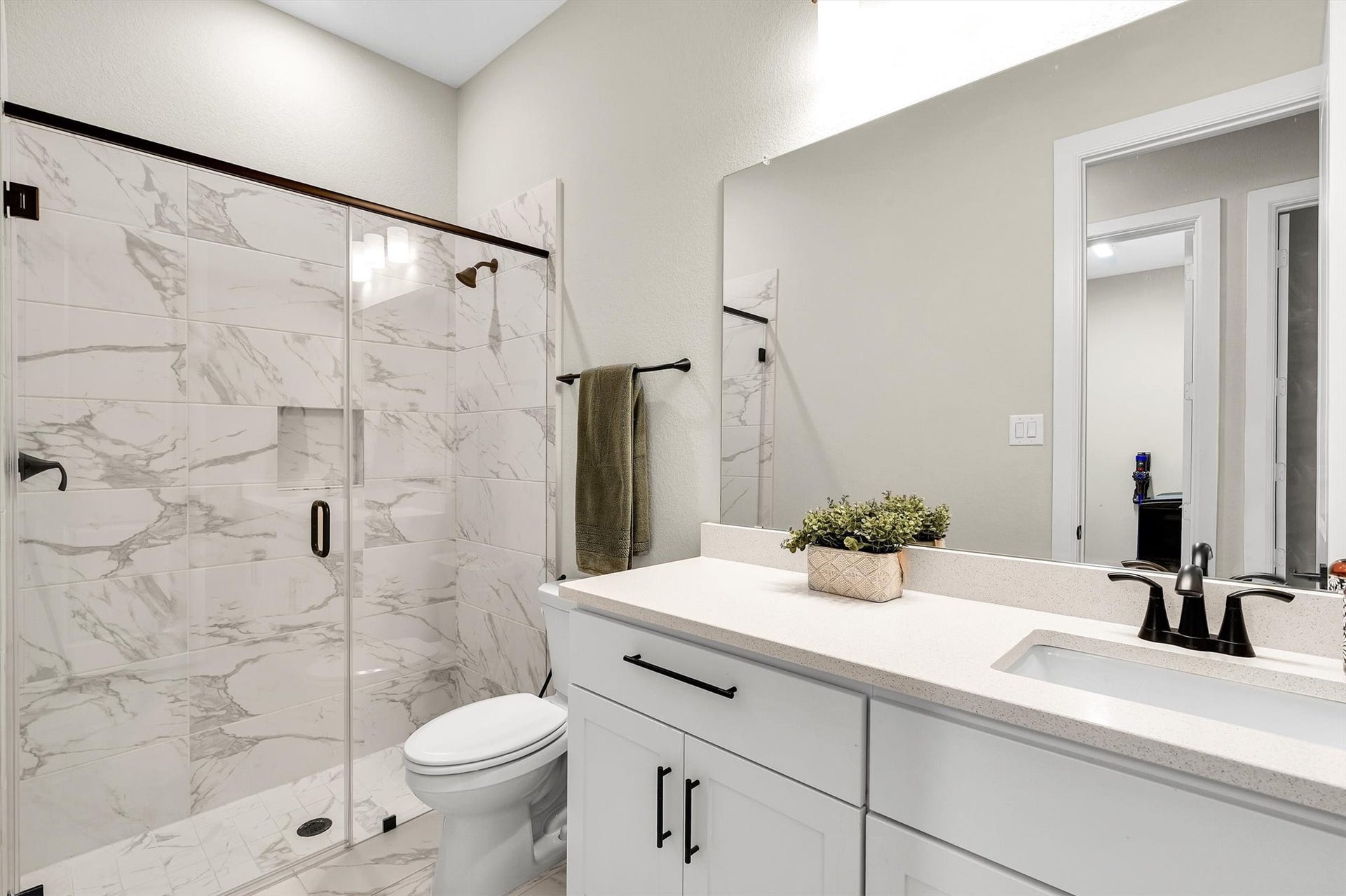 The 2nd full bathroom features a modern design with a spacious walk-in shower, marble-look tiles, a sleek vanity with a large mirror, and contemporary fixtures, creating a clean and inviting space.