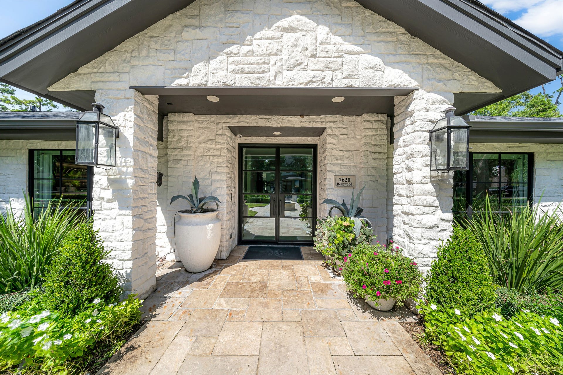 Charming entrance with a stone facade, elegant lanterns, and lush greenery, offering a warm welcome to your new home.