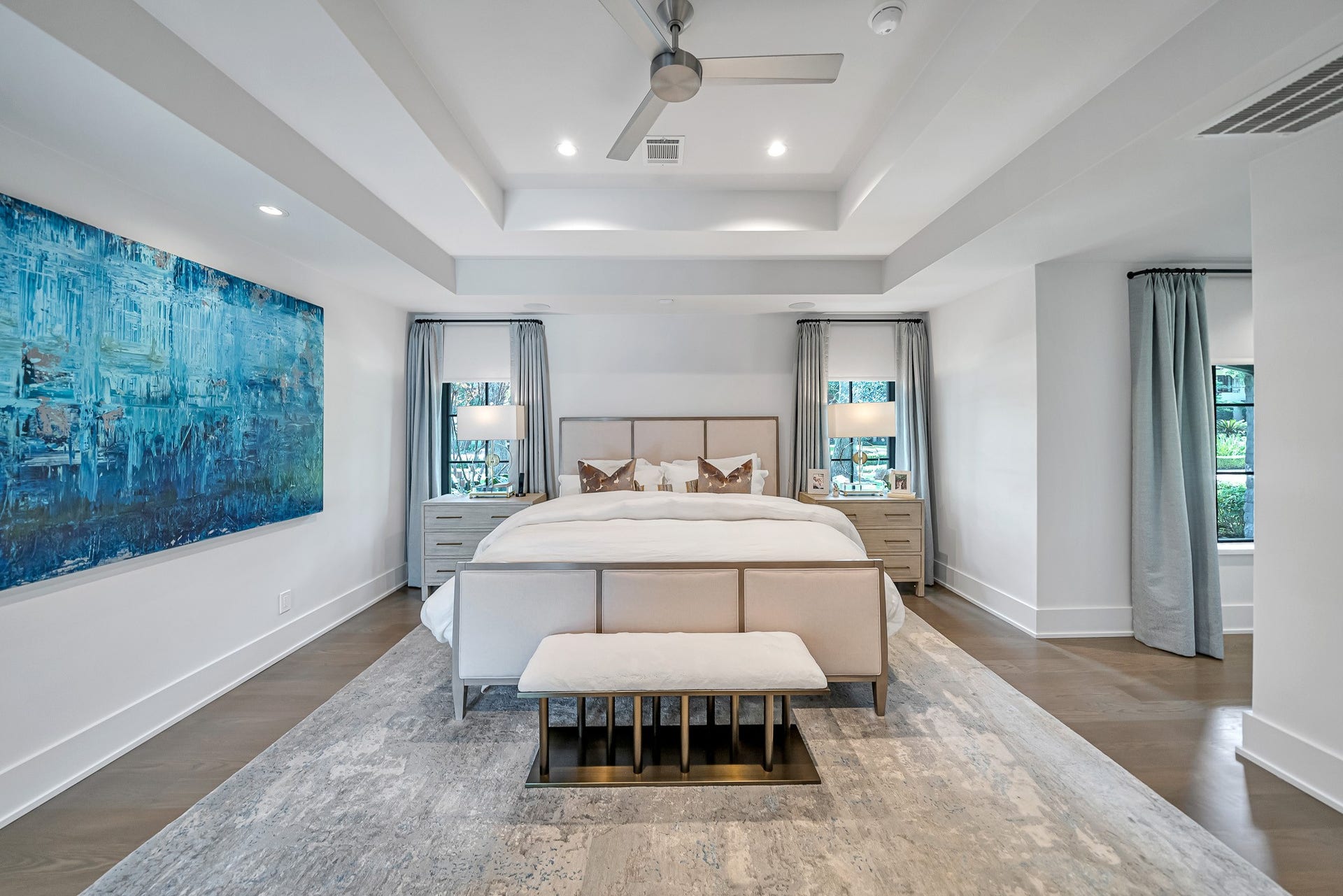 Serene primary suite featuring hardwood floors and a beautifully layered ceiling.