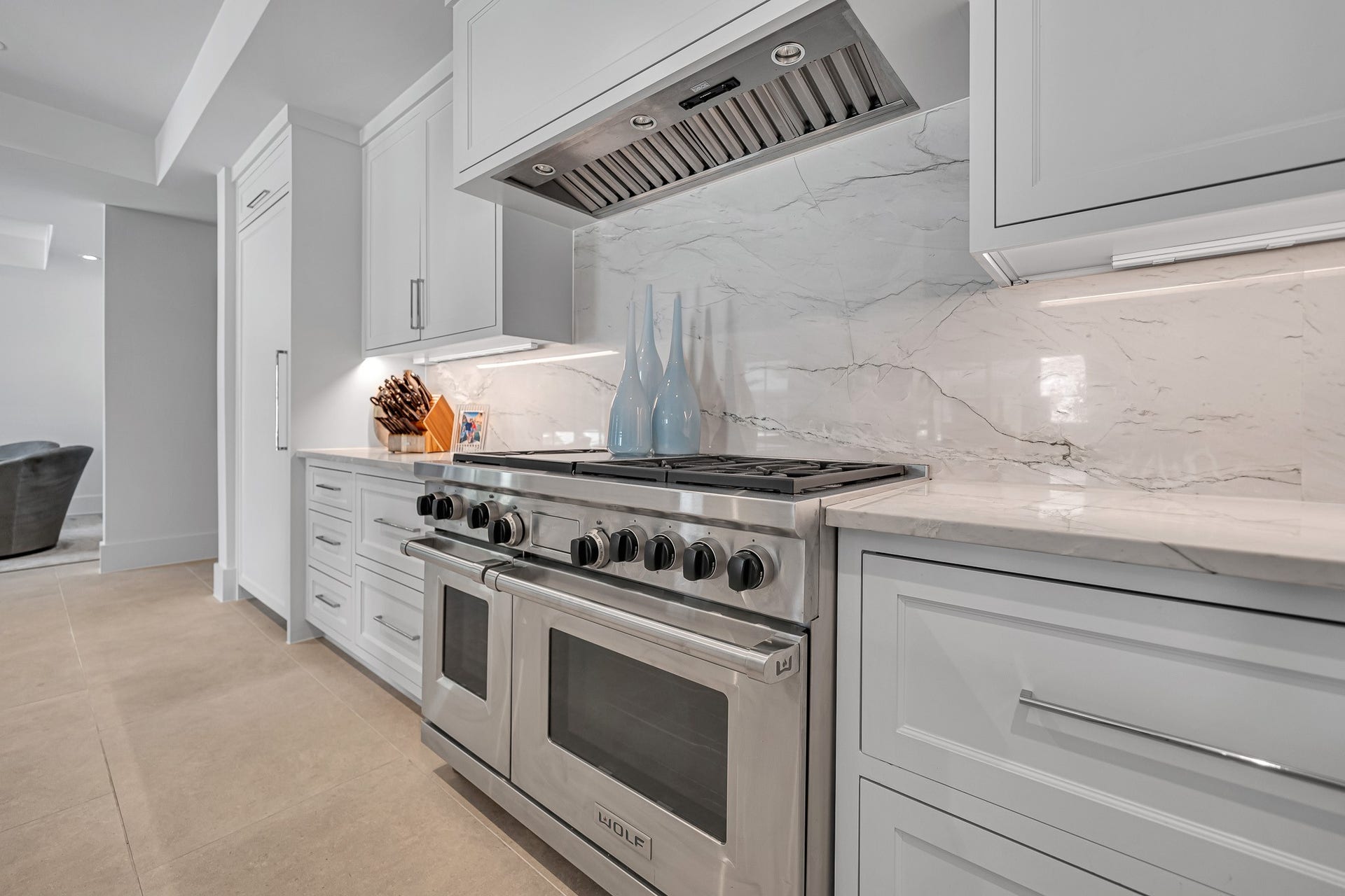 Stainless steel Wolfe range, white cabinetry, and a Quartzite backsplash for a sophisticated touch.