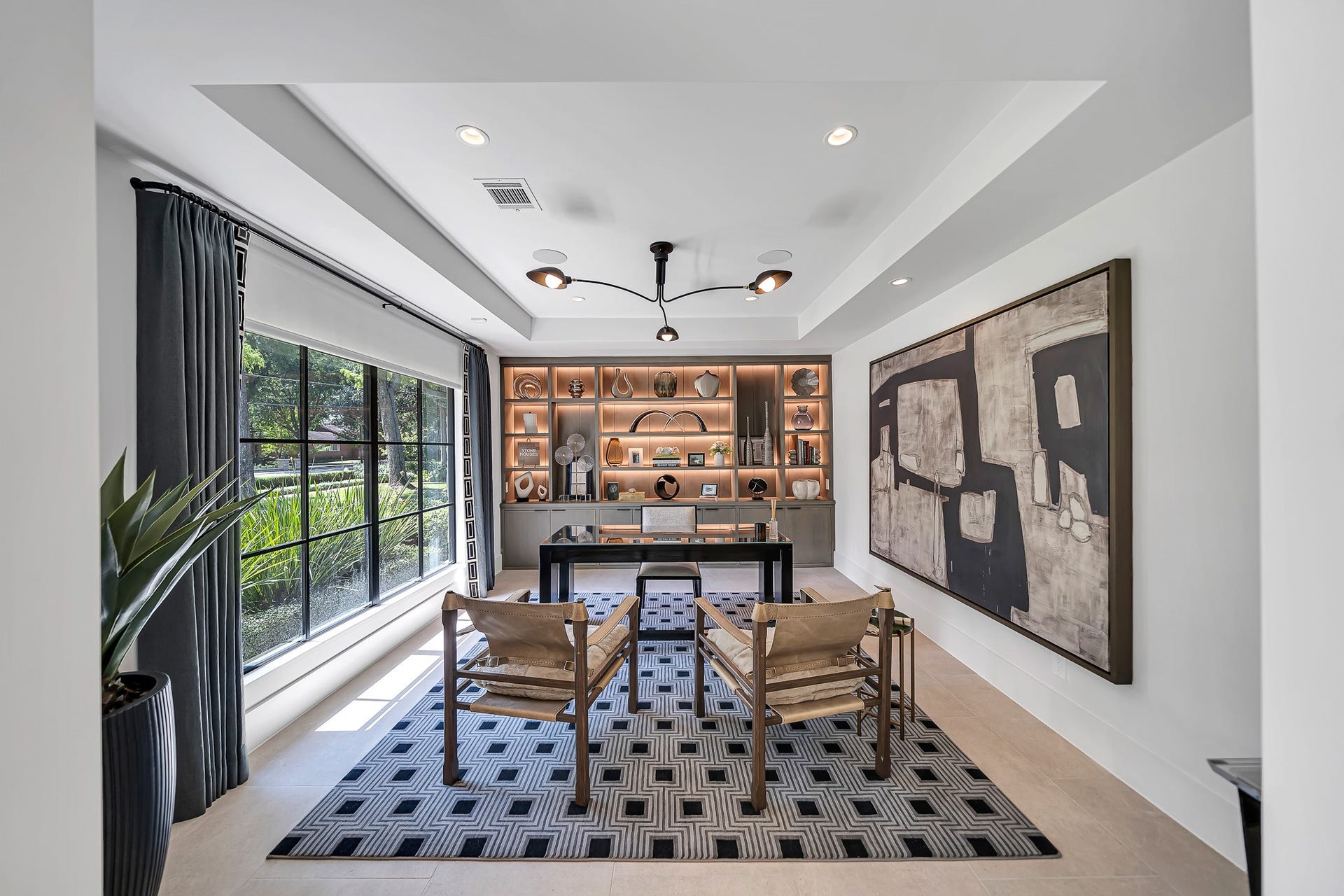 Spacious home office featuring custom built-in cabinetry with integrated lighting, expansive windows overlooking the outdoors, and sophisticated, thoughtfully designed workspace.