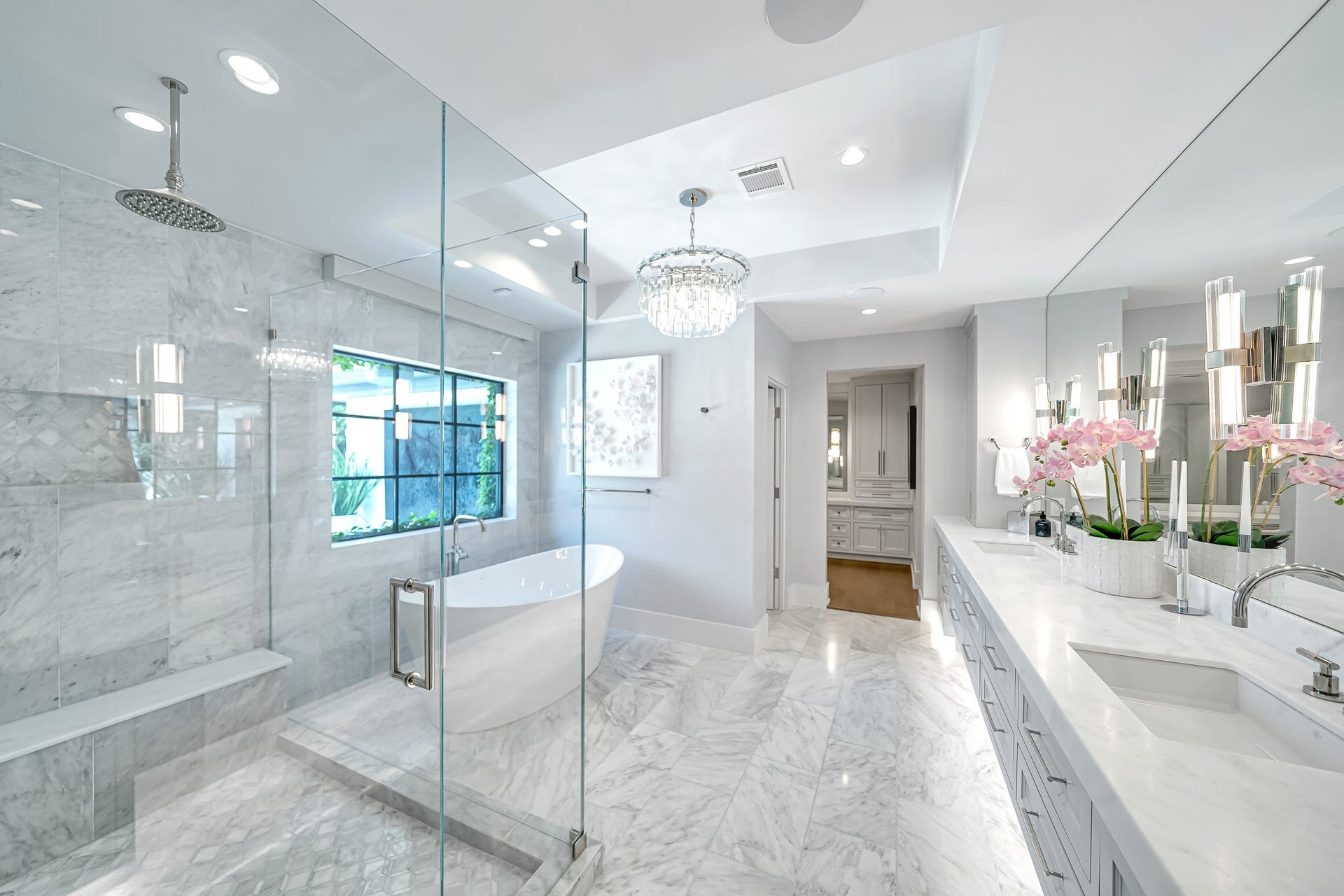 Spa-inspired primary bathroom showcases seamless glass shower and a luxurious soaking tub, completmented by refined finishes and thoughtful design.