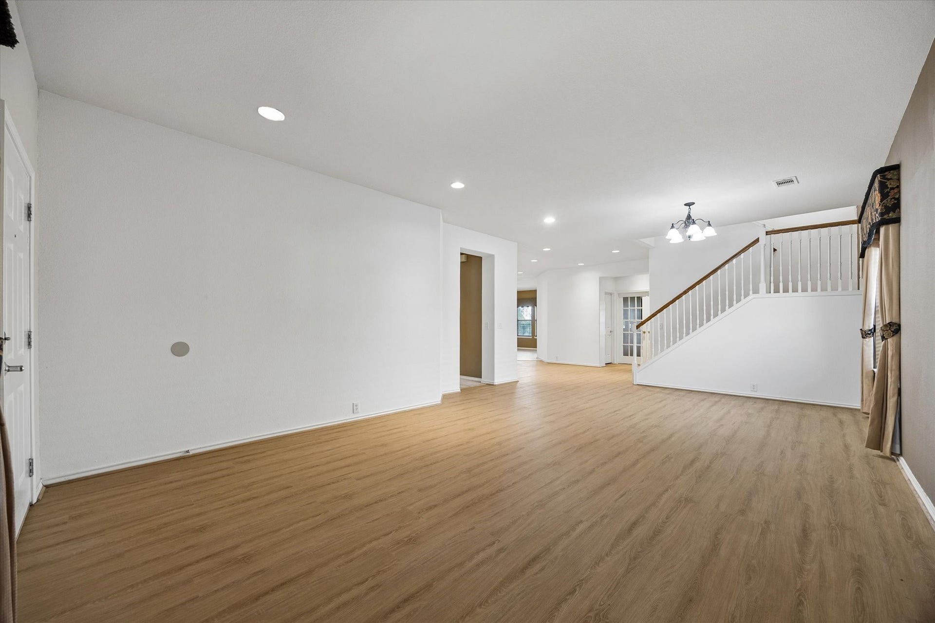 Upon entering you will be greeted by a spacious open-concept living area with elegant wood flooring and recessed lighting, featuring a staircase leading to the upper level.
