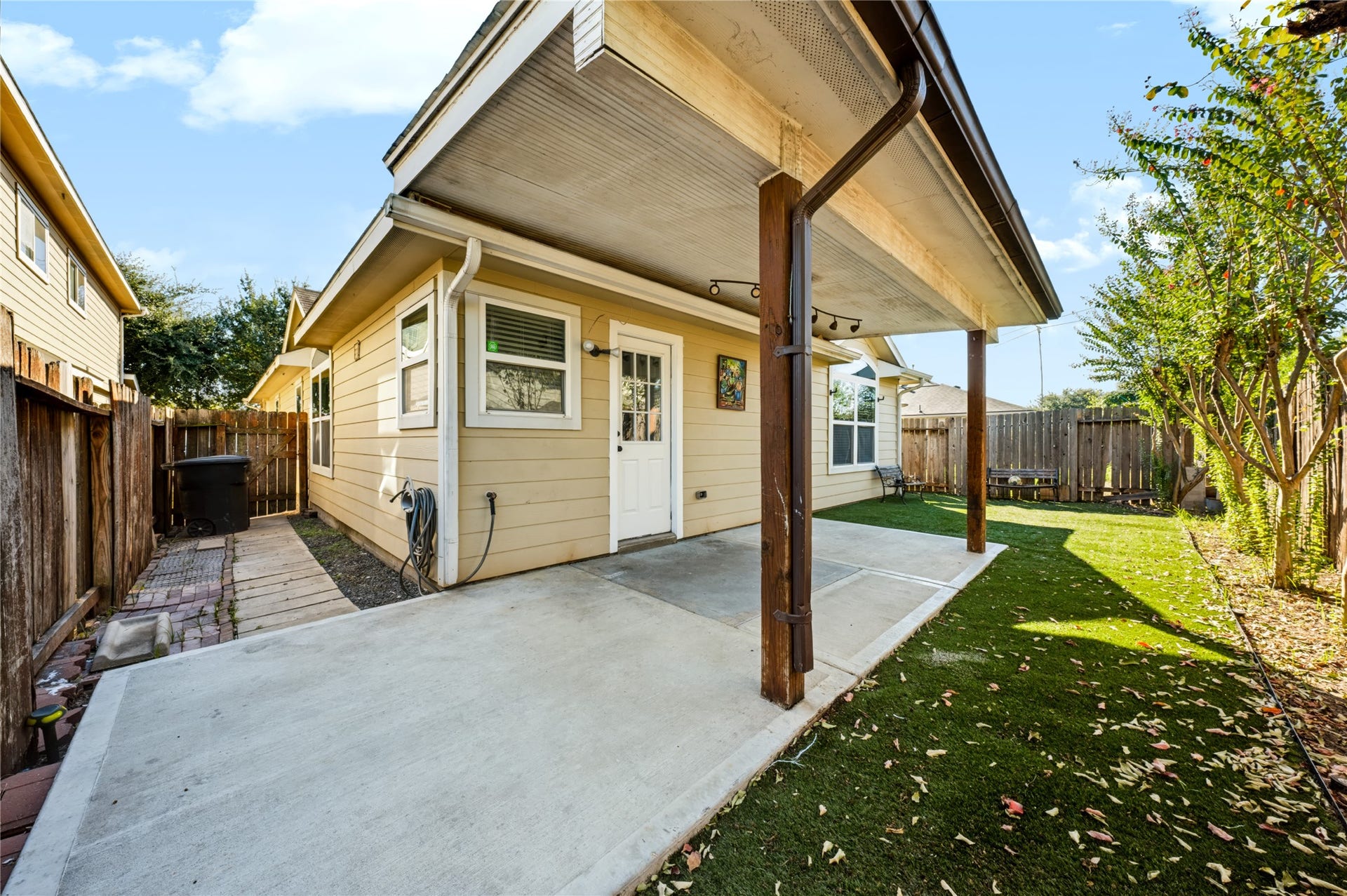 Private backyard featuring a covered back patio, a concrete slab area, and a neatly maintained yardideal for outdoor relaxing or entertaining