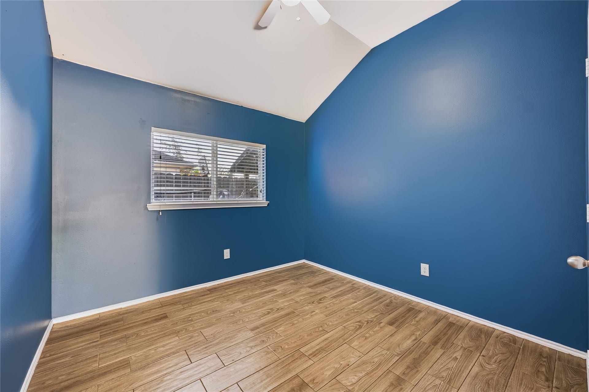 Bright and inviting secondary bedroom featuring rich wood-look tile flooring, a large window with natural light, and a flexible layout.