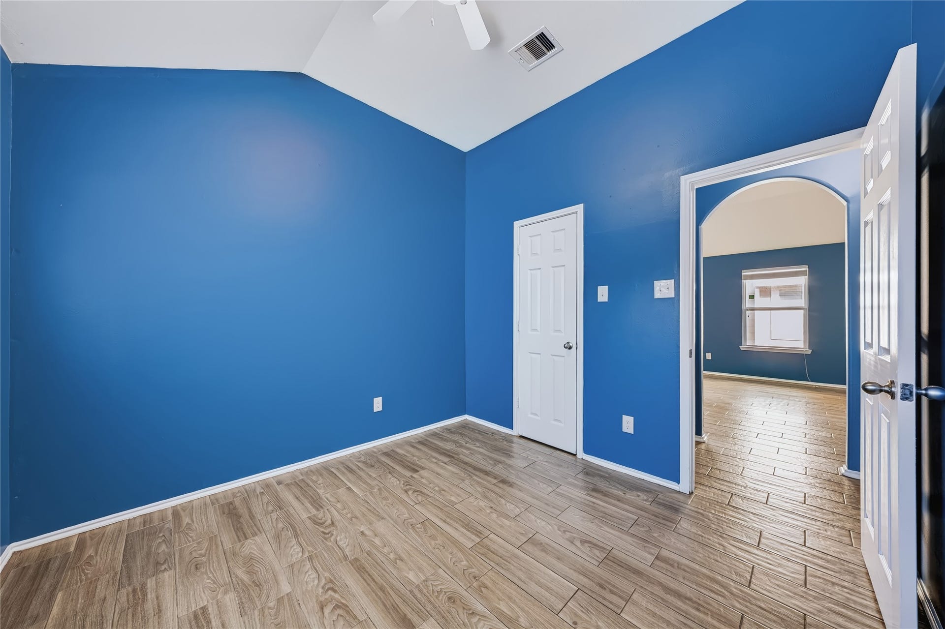 Bright and inviting secondary bedroom featuring rich wood-look tile flooring, a large window with natural light, and a flexible layout.