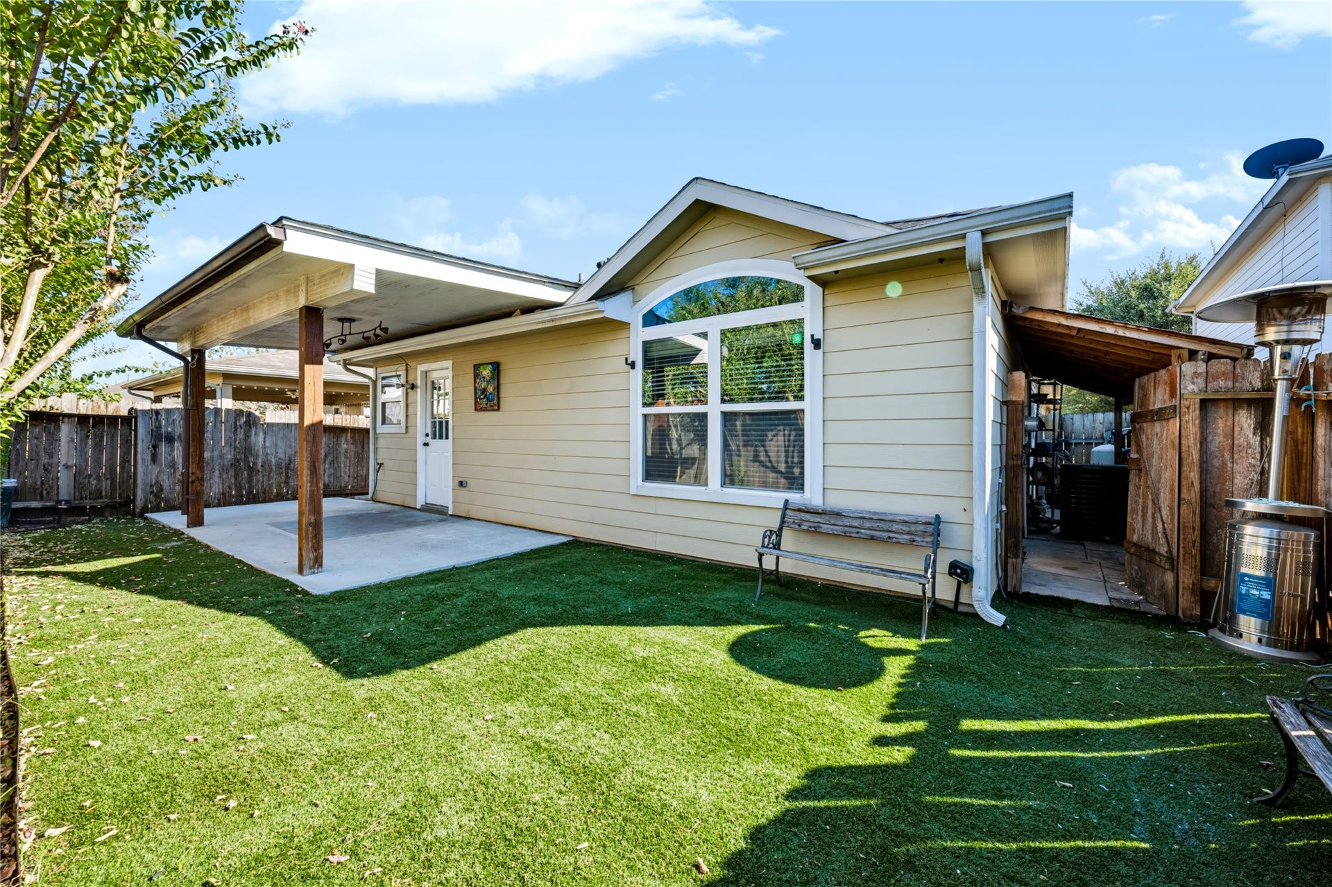 Private backyard featuring a covered back patio, a concrete slab area, and a neatly maintained yardideal for outdoor relaxing or entertaining