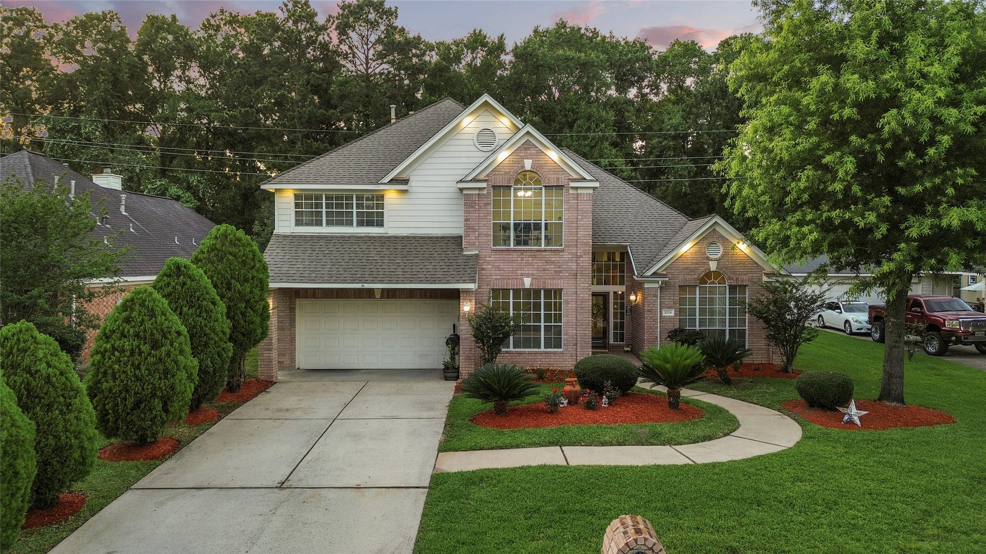 20214 Powerscourt Drive, Humble, TX 77346 This charming two-story home features a classic brick facade with a gabled roof and large windows. The manicured front yard includes neatly trimmed shrubs and a curved walkway, enhancing the inviting curb appeal.