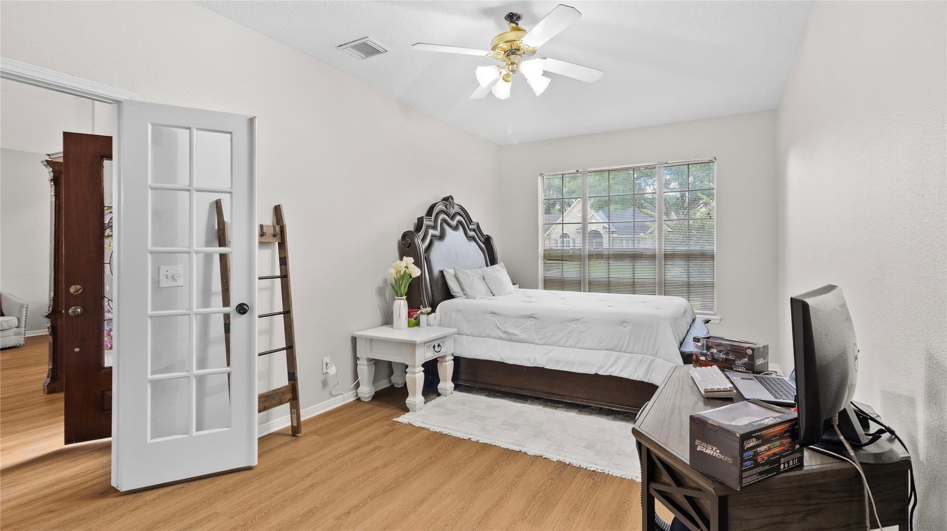 20214 Powerscourt Drive, Humble, TX 77346 Versatile secondary bedroom featuring elegant French doors and warm wood-look flooringideal for a sophisticated home office or study.