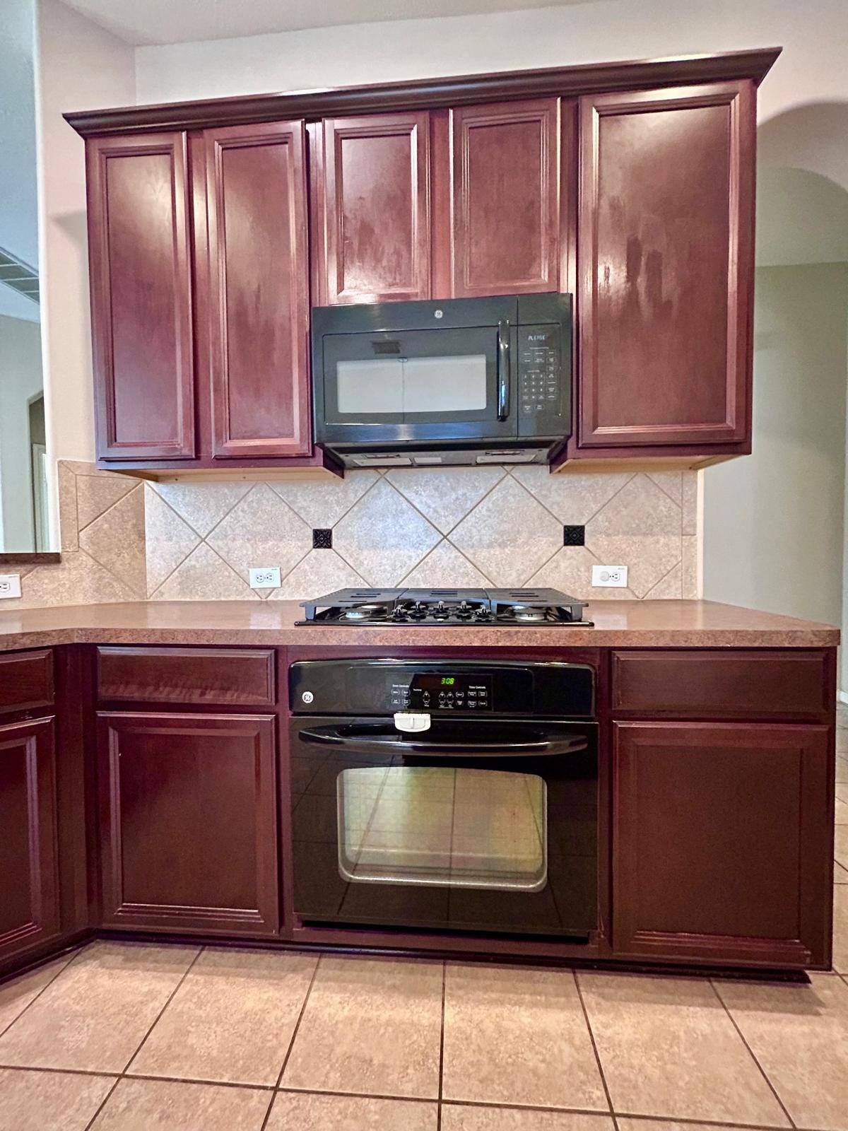 25918 Silver Timbers Lane, Katy, TX 77494 Elegant kitchen features rich wood cabinetry complemented by modern appliances and a stylish tile backsplash.