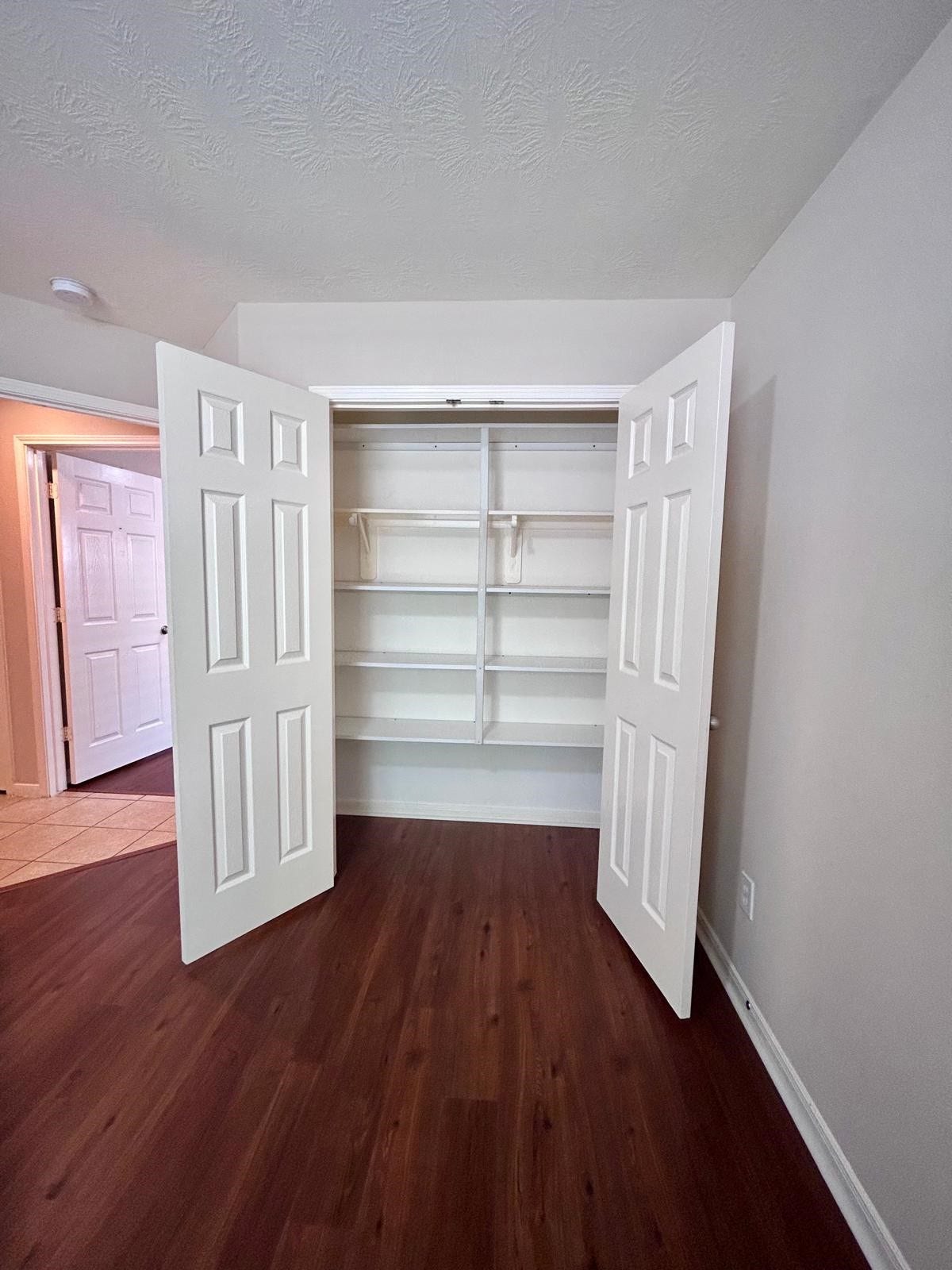 25918 Silver Timbers Lane, Katy, TX 77494 Spacious closet with double doors and built-in shelving, set against rich wood flooring for a stylish storage solution.