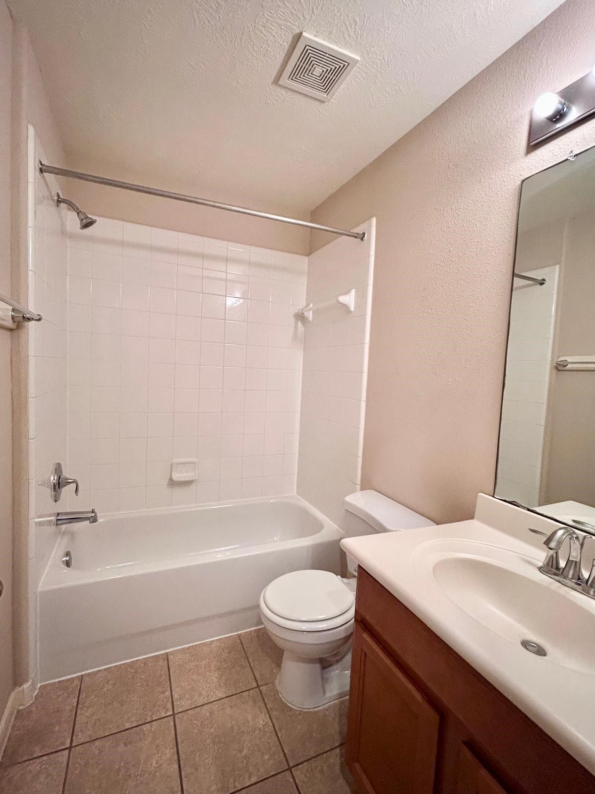 25918 Silver Timbers Lane, Katy, TX 77494 A clean and functional bathroom featuring a sleek white bathtub with a shower, a large mirror above a modern vanity, and neutral tile flooring for a fresh, inviting look.