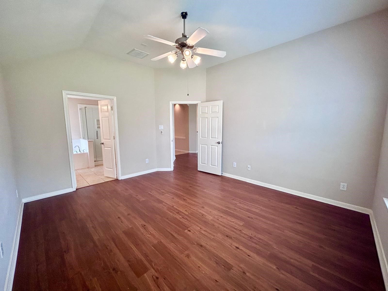25918 Silver Timbers Lane, Katy, TX 77494 Spacious room with rich wood flooring, high ceilings, and a ceiling fan, leading to a tiled ensuite bathroom.