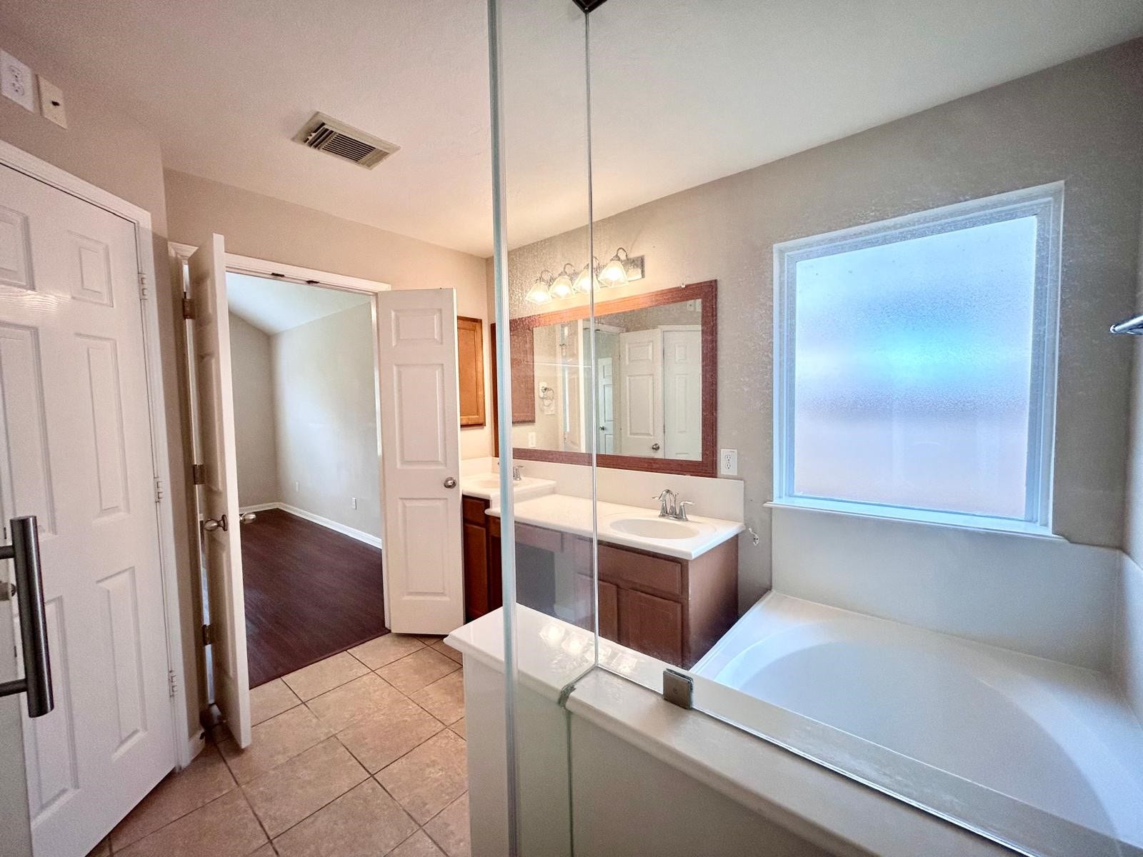 25918 Silver Timbers Lane, Katy, TX 77494 Bright and spacious bathroom featuring a large soaking tub, a sleek vanity with ample counter space, and a frosted window for privacy.