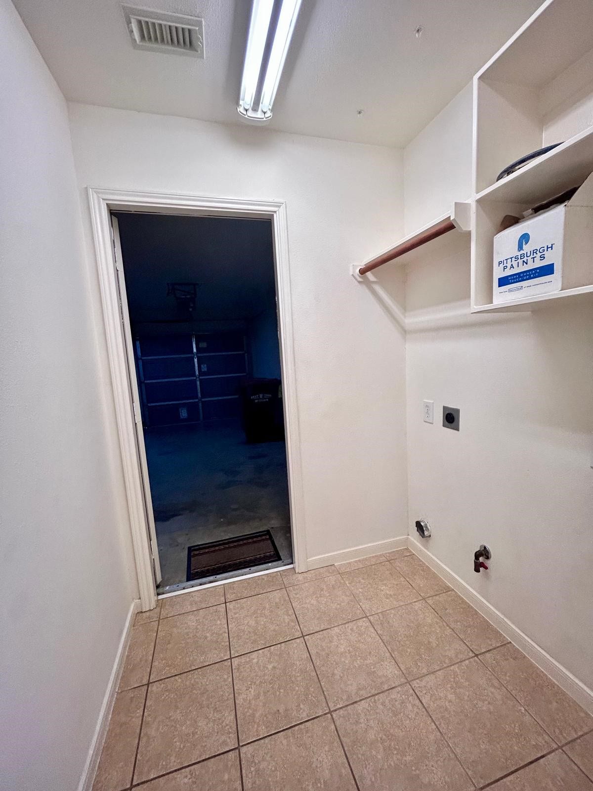 25918 Silver Timbers Lane, Katy, TX 77494 Convenient laundry room with tile flooring, shelving, and a door leading to the garage.