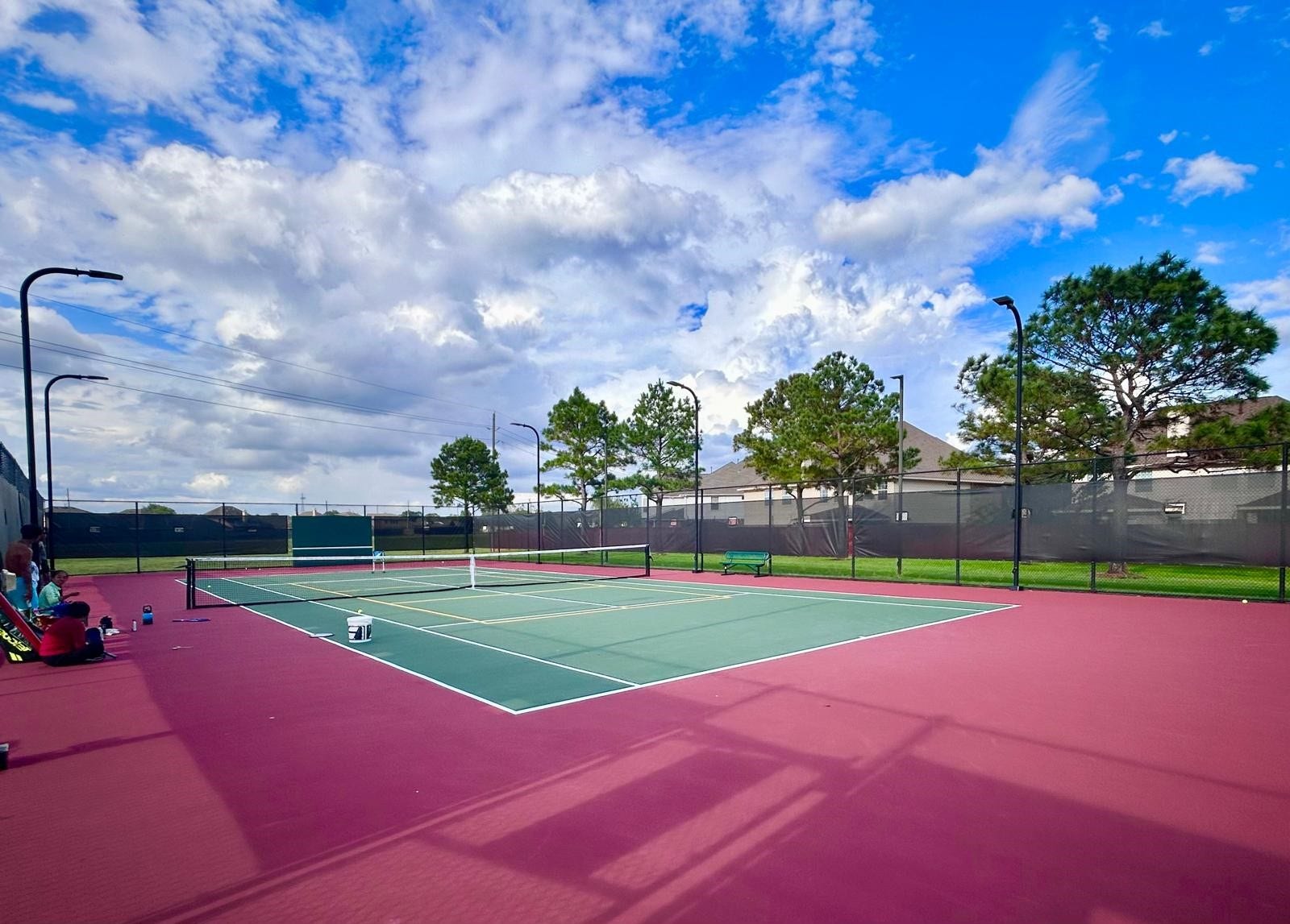 25918 Silver Timbers Lane, Katy, TX 77494 Enjoy a game of tennis on this well-maintained court surrounded by lush greenery and a clear blue sky, perfect for outdoor recreation.