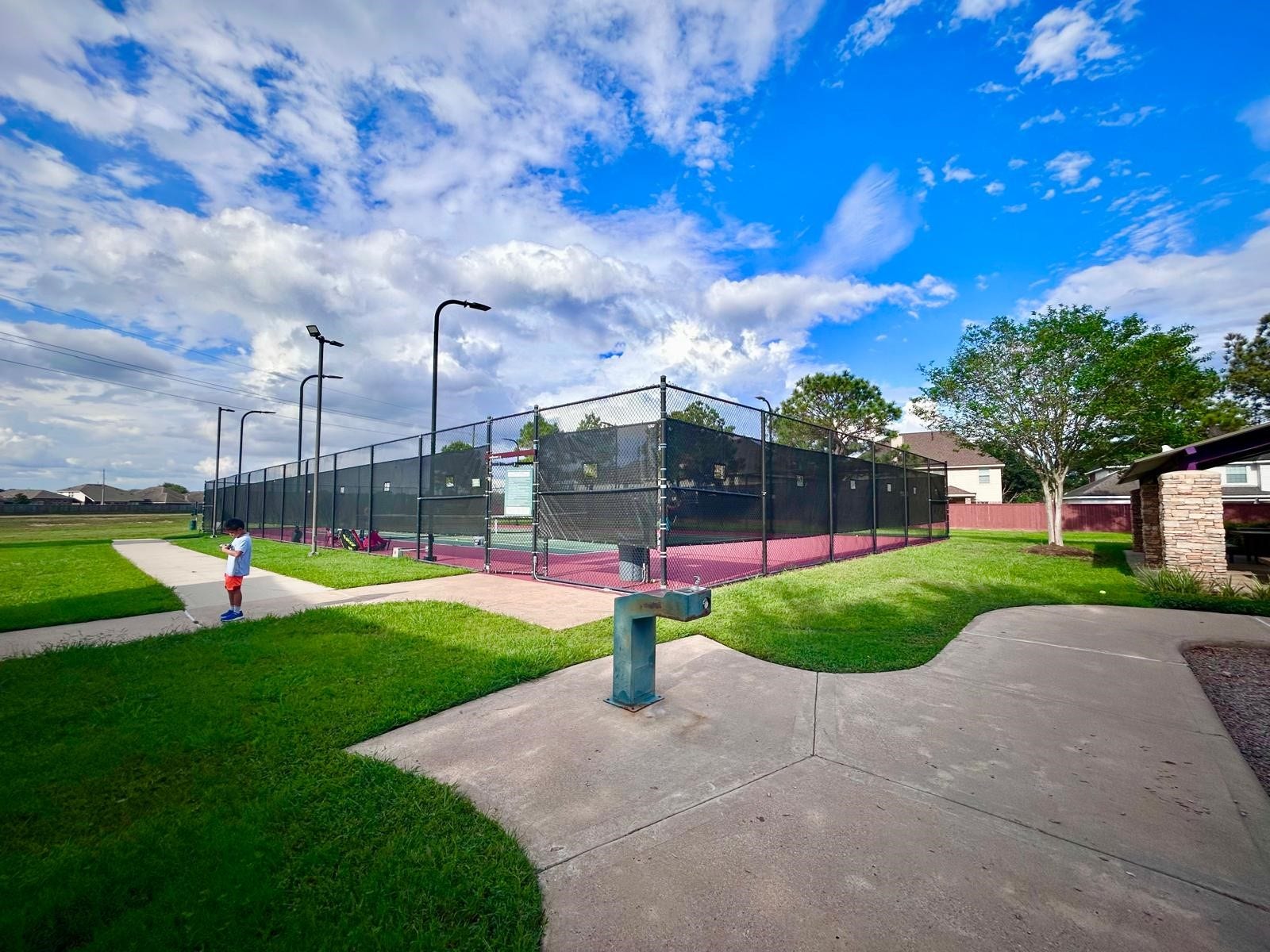25918 Silver Timbers Lane, Katy, TX 77494 Enjoy outdoor activities with access to a well-maintained tennis court surrounded by lush greenery and open skies, perfect for sports enthusiasts.