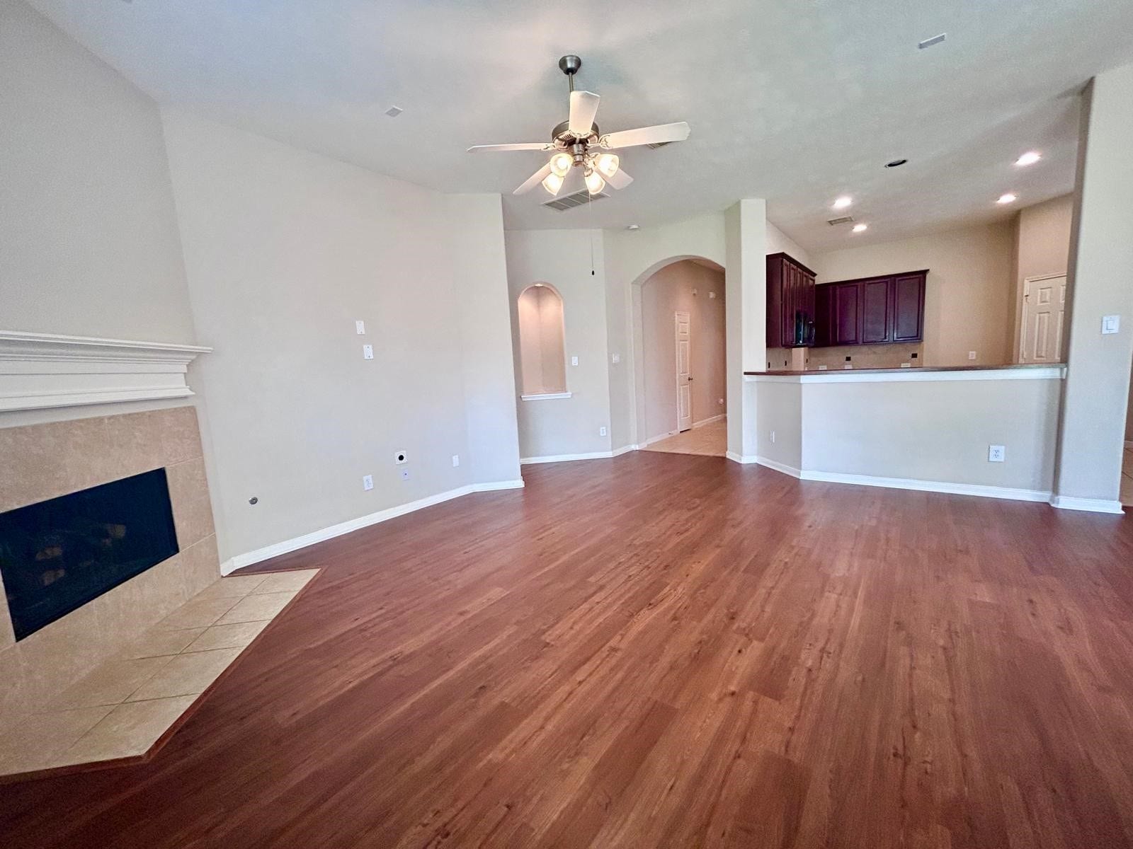 25918 Silver Timbers Lane, Katy, TX 77494 Spacious living area with rich wood flooring, featuring a cozy fireplace and an open layout leading to the kitchen with elegant cabinetry.