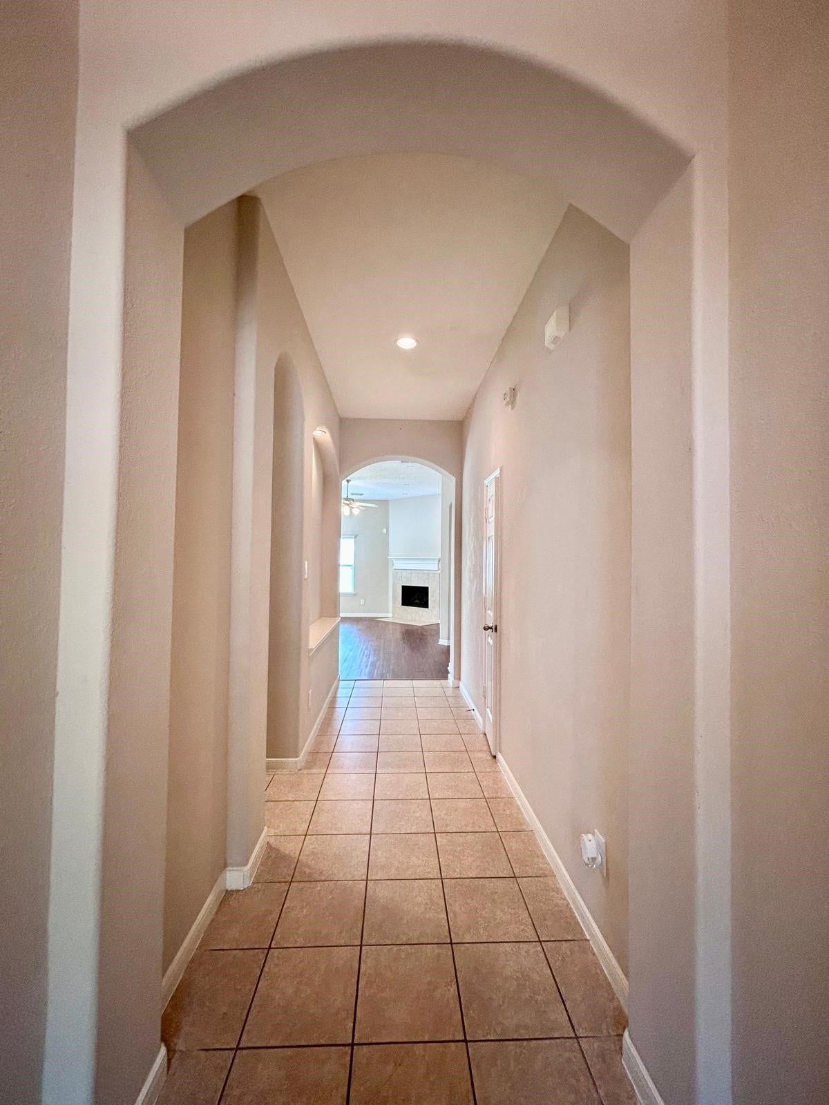 25918 Silver Timbers Lane, Katy, TX 77494 Inviting hallway with elegant archways and tile flooring leads to a spacious living area, featuring a cozy fireplace.