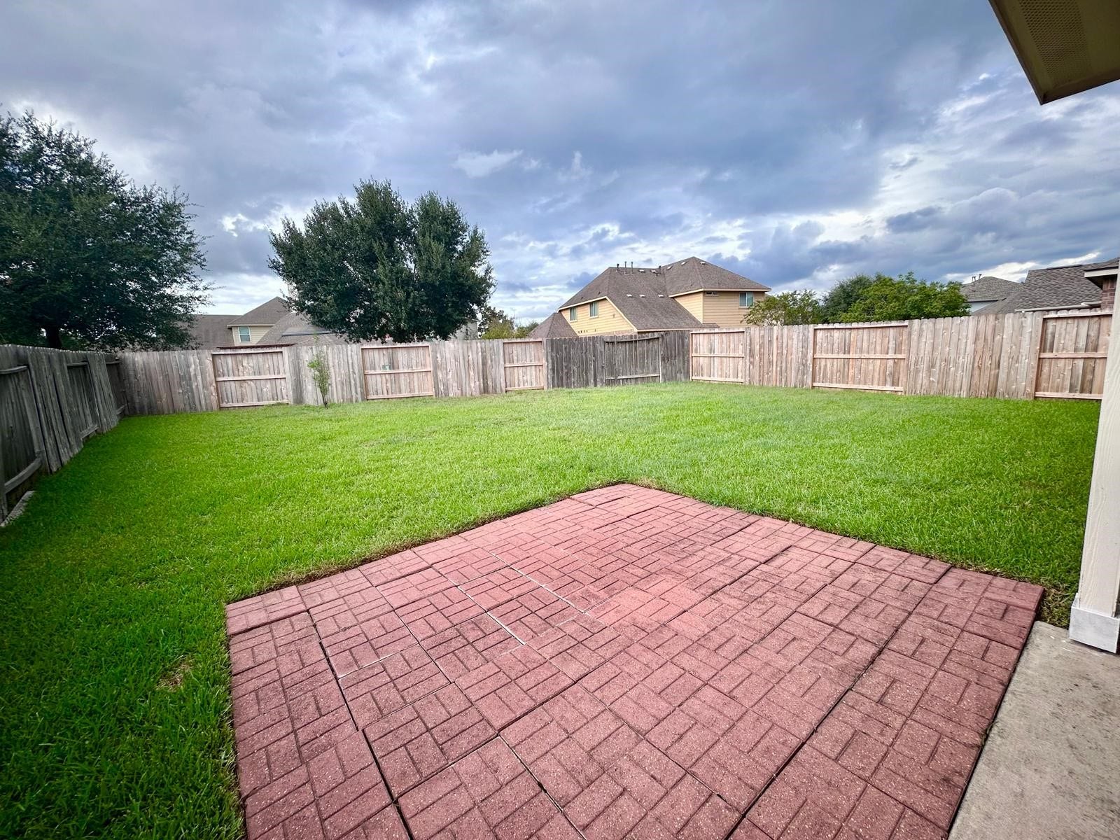 25918 Silver Timbers Lane, Katy, TX 77494 Spacious backyard with a well-maintained lawn and a charming brick patio, perfect for outdoor gatherings and relaxation.