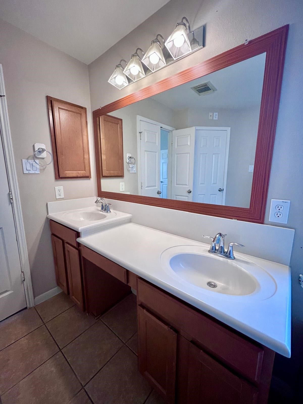 25918 Silver Timbers Lane, Katy, TX 77494 Spacious bathroom featuring a double vanity with sleek sinks, rich wood cabinetry, and a large mirror with modern lighting.