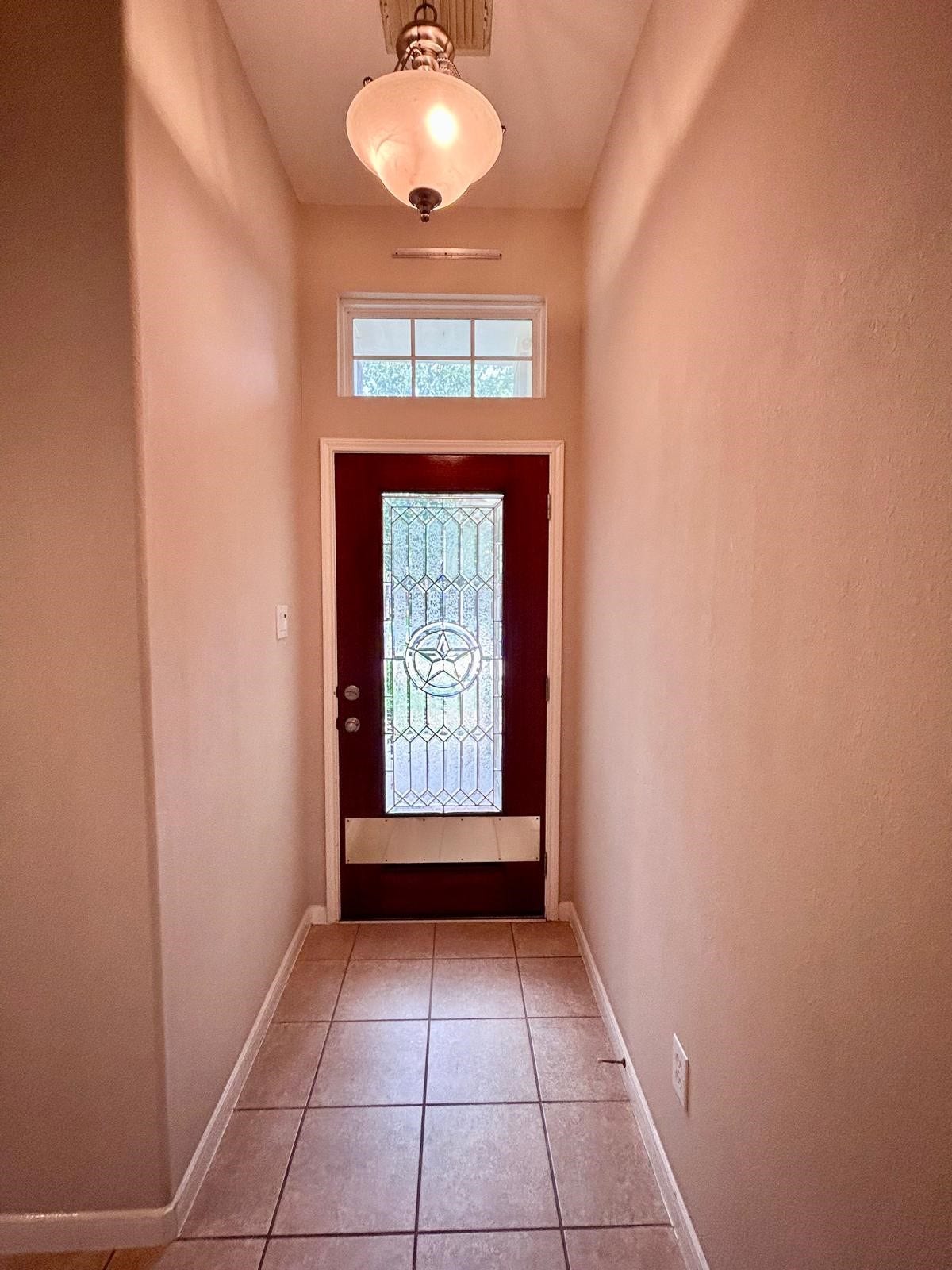 25918 Silver Timbers Lane, Katy, TX 77494 Elegant entrance with a rich wooden door featuring a decorative glass panel and a star design, complemented by a tiled floor.