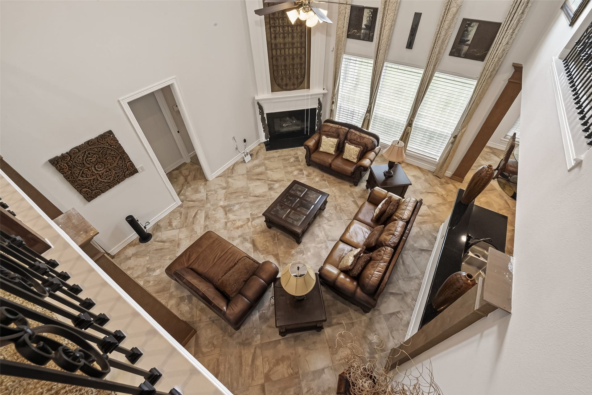 1814 Bartrum Street, Sugar Land, TX 77479 Spacious living room with high ceilings, an elegant fireplace, and abundant natural light from large windows. Luxurious leather seating and sophisticated tile flooring create a warm, inviting atmosphere.