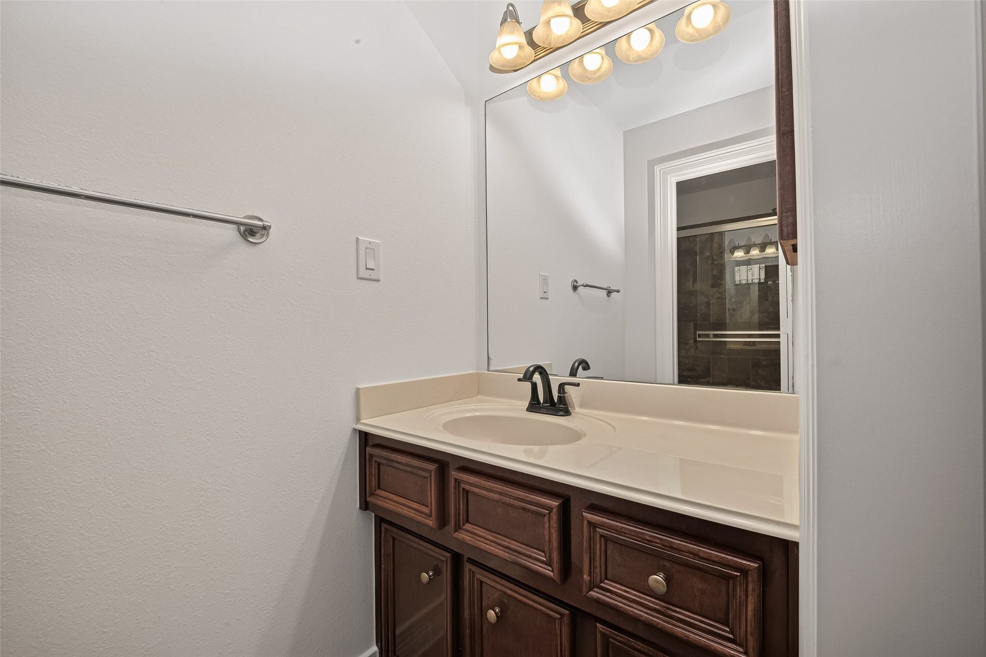 1814 Bartrum Street, Sugar Land, TX 77479 Elegant bathroom featuring a sleek vanity with a dark wood cabinet, modern fixtures, and a large mirror under warm lighting.