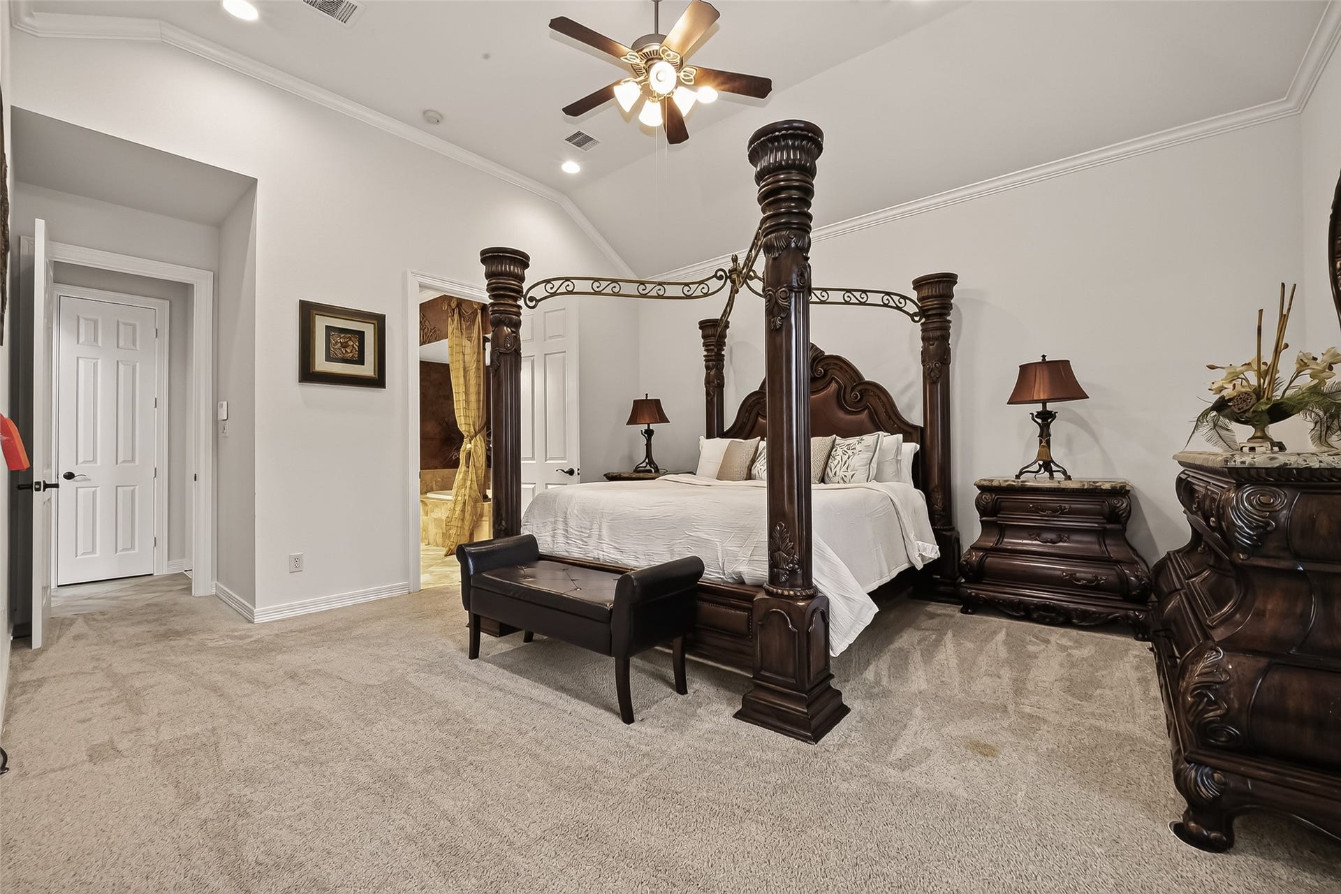 1814 Bartrum Street, Sugar Land, TX 77479 Luxurious primary bedroom featuring an elegant canopy bed with intricate wooden posts, plush carpeting, and soft ambient lighting for a cozy retreat.