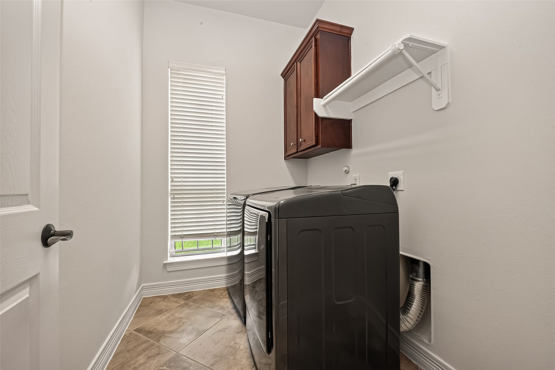 1814 Bartrum Street, Sugar Land, TX 77479 Modern laundry room with sleek appliances, ample cabinetry, and natural light from a tall window.