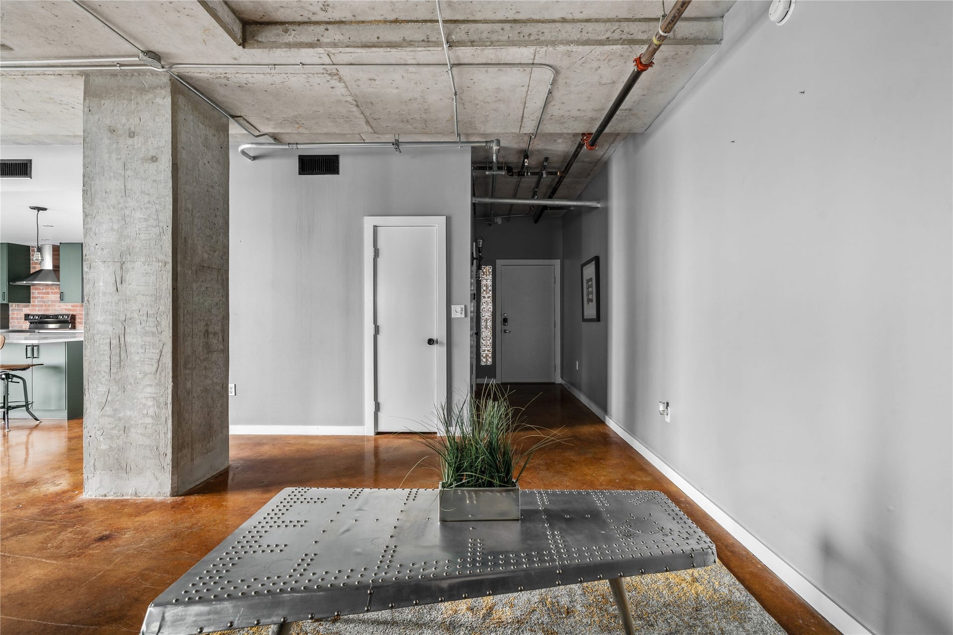 The entry opens into the lofts main living spaces, where polished concrete floors and exposed ceilings immediately establish its authentic industrial character.