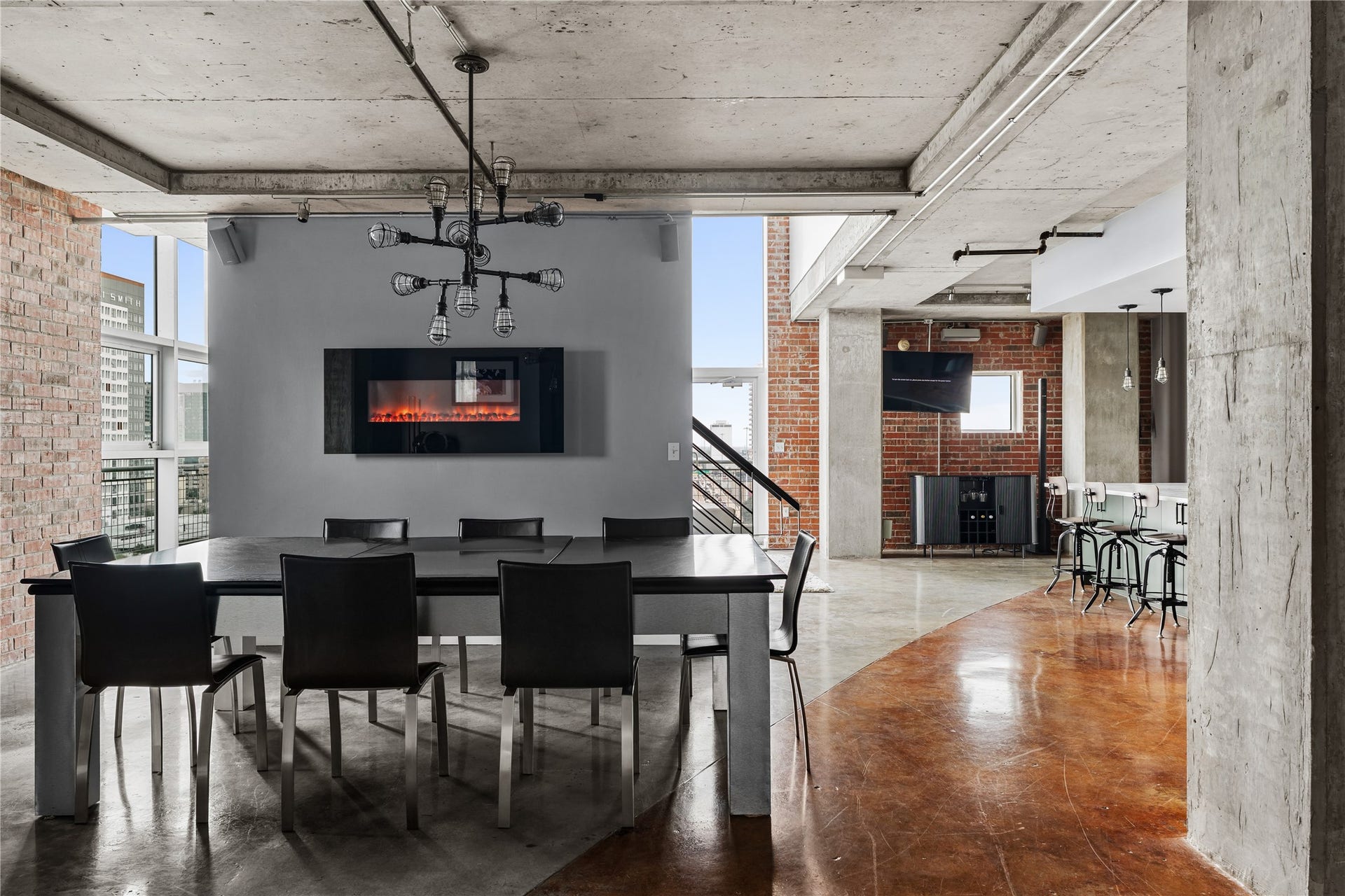 The dining area sits at the center of the lofts open layout, framed by exposed concrete ceilings and columns with a seamless connection to the remodeled kitchen and surrounding living spaces.