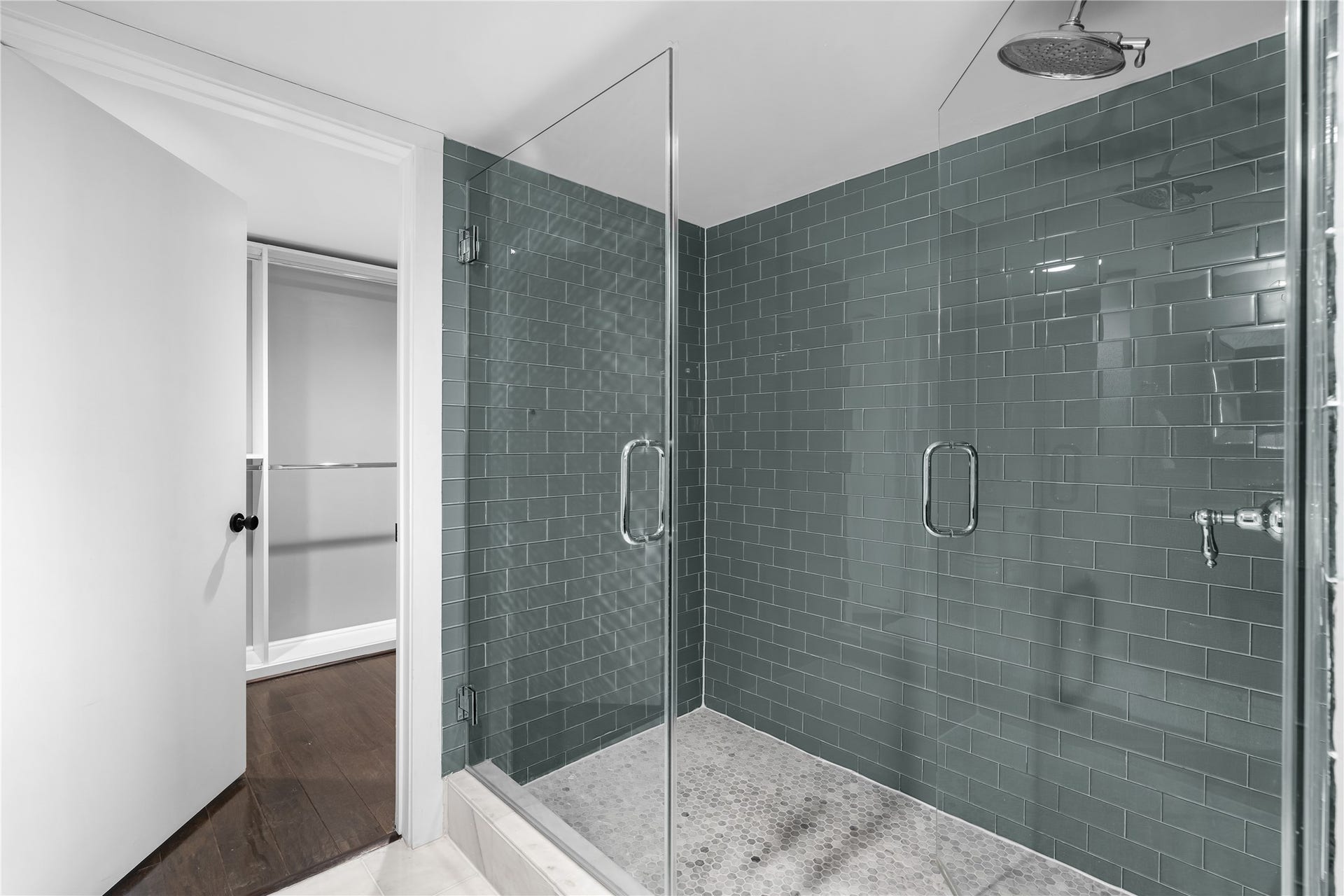 The oversized glass enclosed shower becomes a standout feature of the remodeled primary bath, finished with floor to ceiling tile and a clean, contemporary design.
