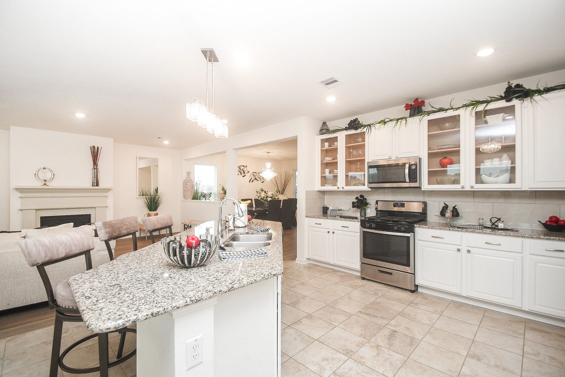 22523 Strathmore Drive, Richmond, TX 77469 Bright and spacious open-concept kitchen with granite countertops, modern stainless-steel appliances, beautiful pendant lighting and ample cabinet space. It flows seamlessly into a cozy living area with a fireplace, perfect for entertaining.