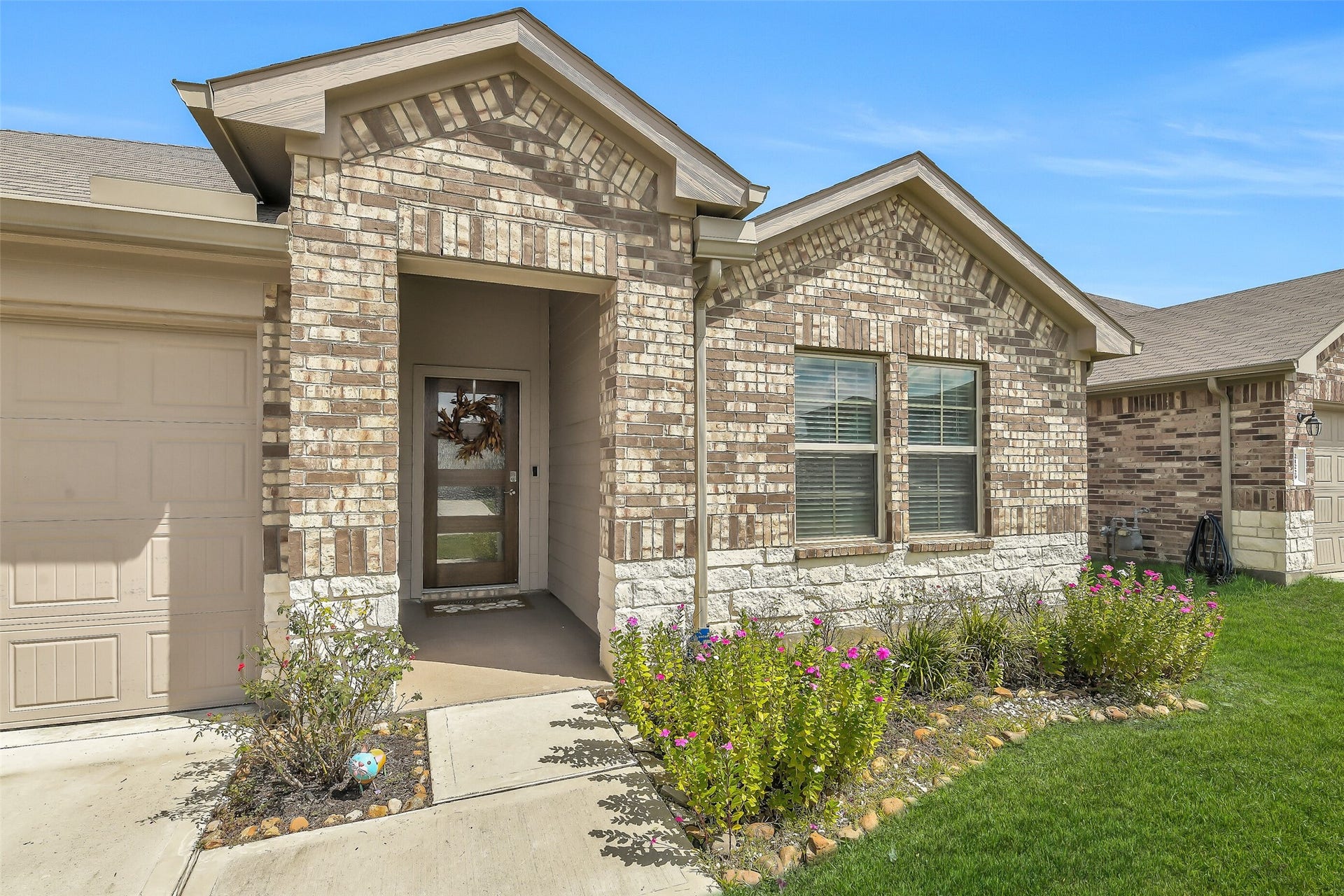 21225 Ivy Woods Court, New Caney, TX 77357 Charming brick and stone exterior with a welcoming front porch and Updated front door accented by well-maintained landscaping and a vibrant lawn.