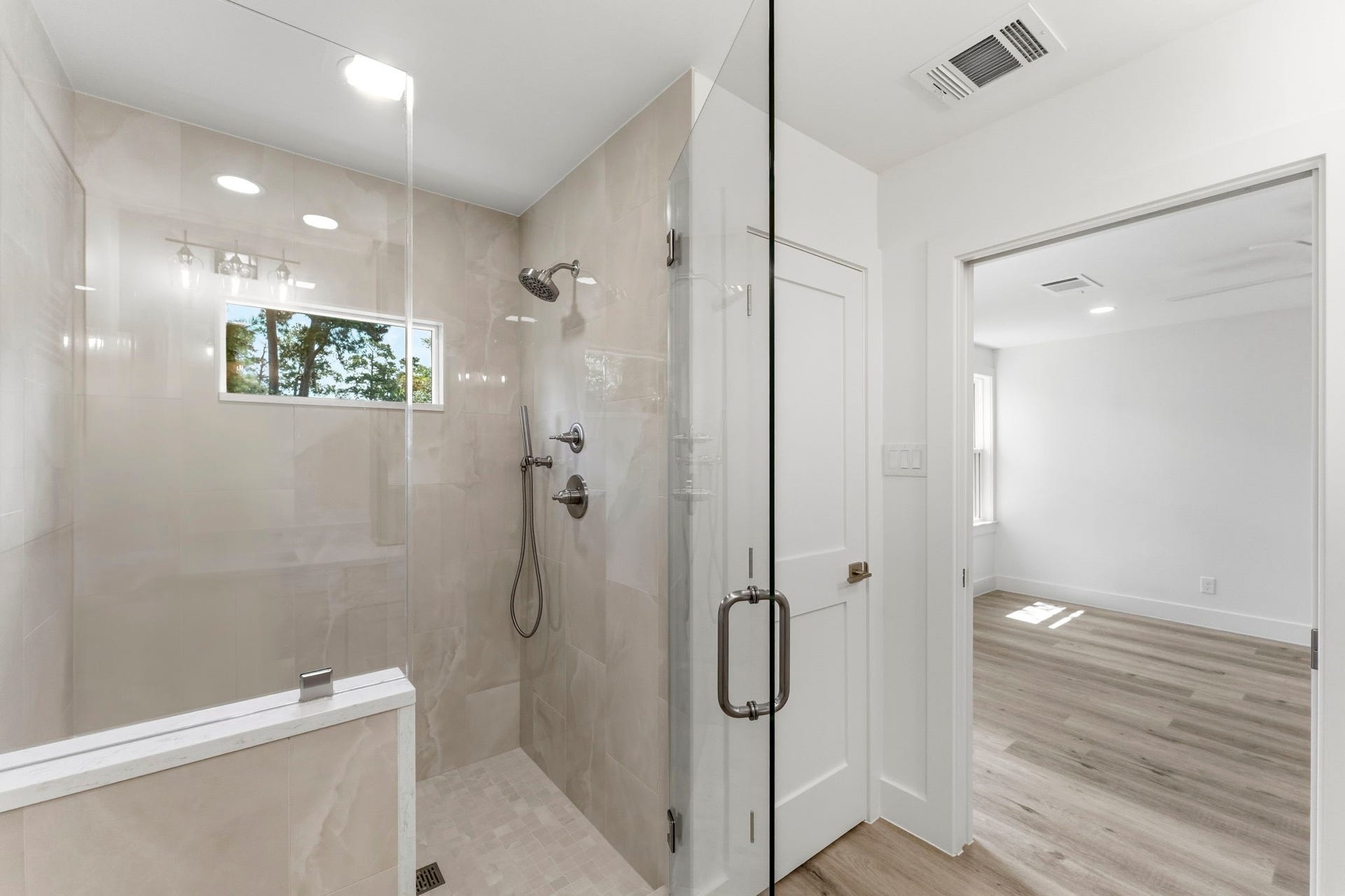 76 Woodhaven Wood Drive, The Woodlands, TX 77380 The luxurious primary features a spacious frameless glass walk-in shower beautifully finished with designer tile extending to the ceiling.