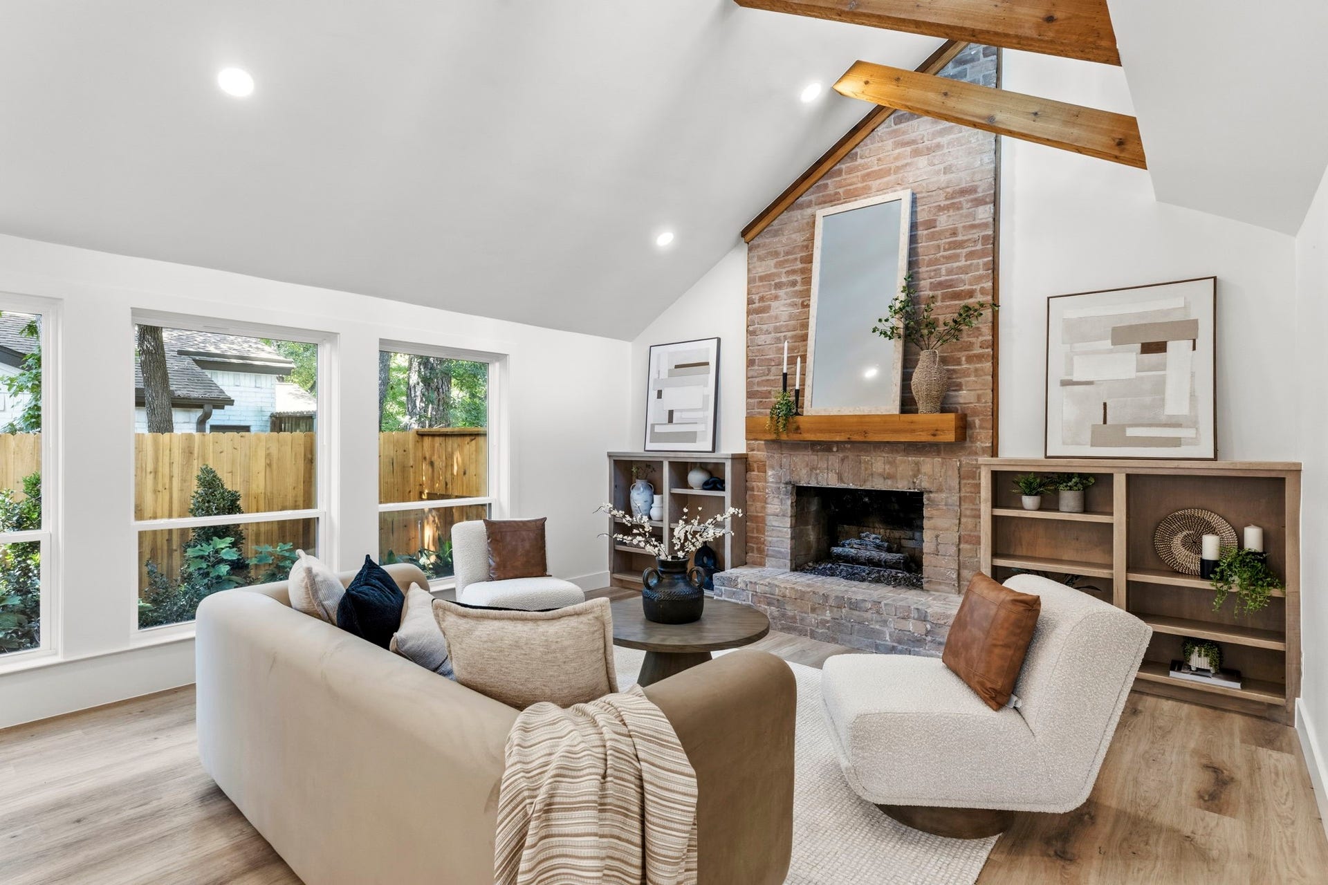 76 Woodhaven Wood Drive, The Woodlands, TX 77380 The dramatic floor-to-ceiling brick fireplace anchors the living room, creating a striking architectural centerpiece beneath the soaring vaulted ceiling.
