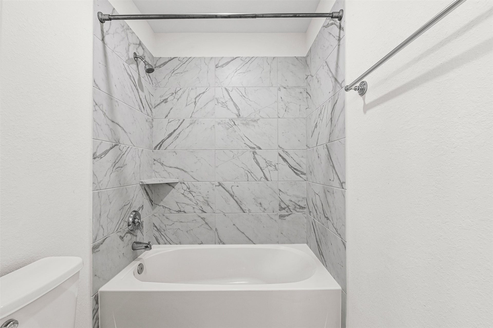 28314 Emerald Bend, Spring, TX 77386 Luxurious floor-to-ceiling marble-patterned tile surrounds this soaking tub and shower combination, bringing a sleek spa aesthetic to the bathroom. Modern chrome fixtures and a built-in display shelf complete the elegant, light-filled space.