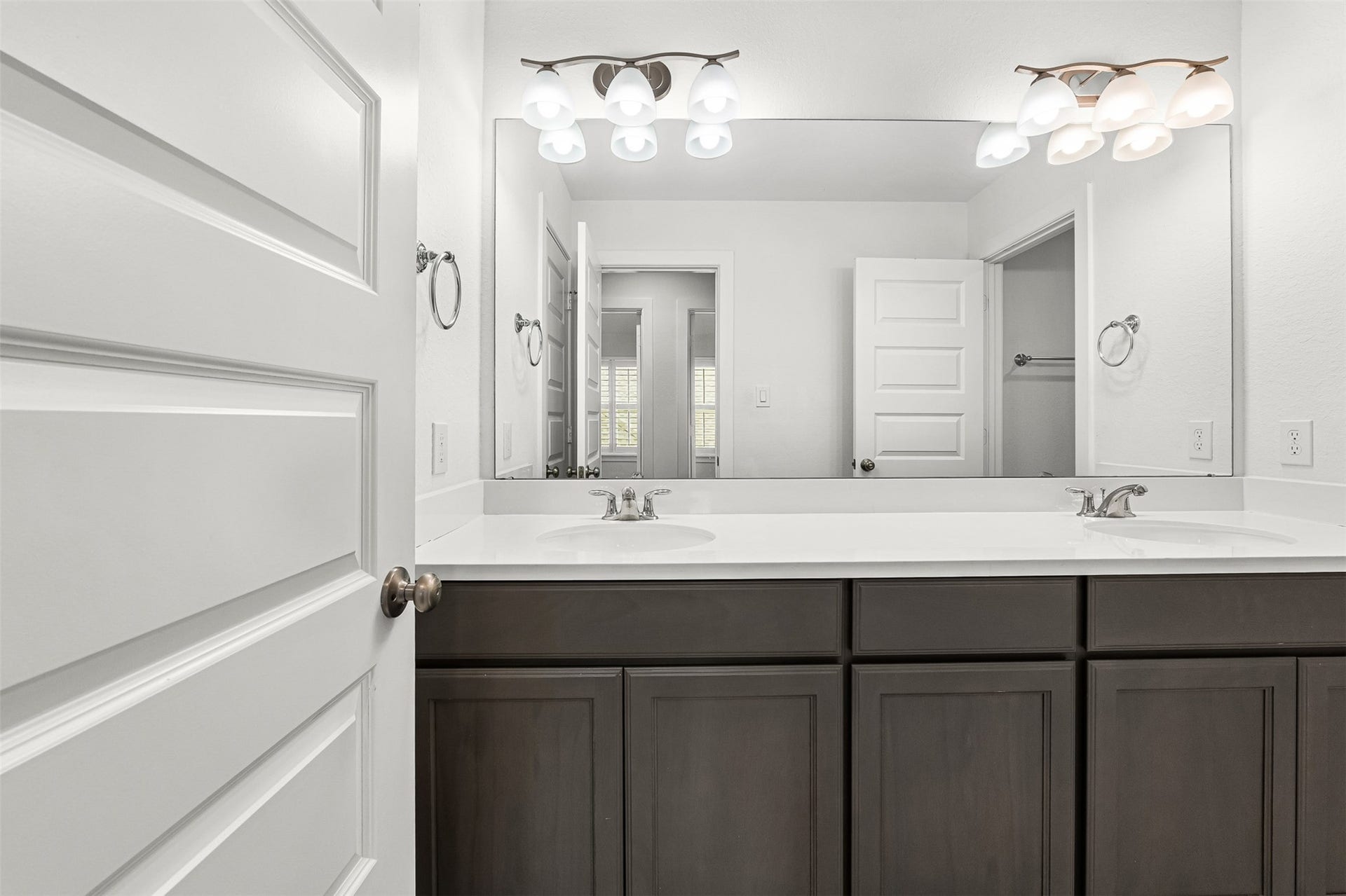28314 Emerald Bend, Spring, TX 77386 A dark contrast vanity with dual sinks and white quartz countertops creates a striking focal point in this secondary full bathroom. Modern multi-light sconces, a full-width mirror, and classic brushed nickel hardware complete the sleek, organized design.