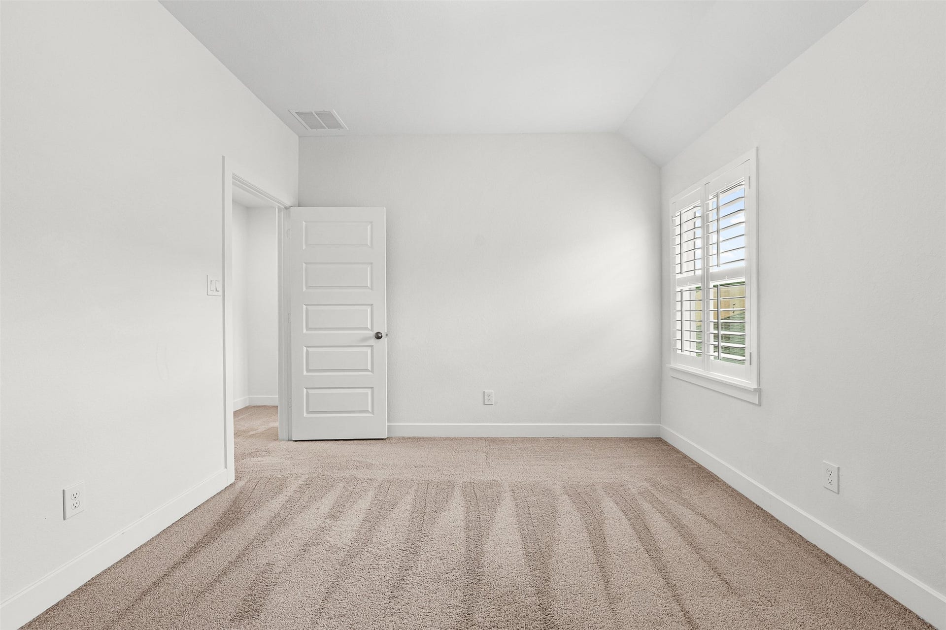 28314 Emerald Bend, Spring, TX 77386 Crisp plantation shutters frame the window in this secondary bedroom, featuring soft carpet flooring and classic neutral walls. Sloped ceiling accents add architectural depth to the versatile layout.