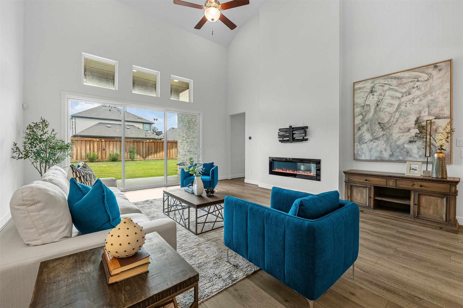 28314 Emerald Bend, Spring, TX 77386 Framed by soaring double-height ceilings, this spacious living room features a sleek linear fireplace and wood-look plank floors. Sliding glass doors and transom windows bring in natural light while opening directly to the private covered patio and green yard.
