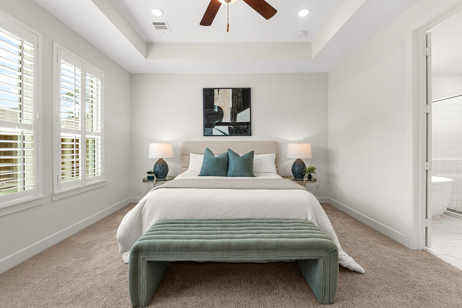 28314 Emerald Bend, Spring, TX 77386 An elegant tray ceiling with a stylish fan crowns this first-floor primary suite, where soft neutral carpeting adds warmth to the expansive layout. White plantation shutters frame bright windows, and direct access to the luxurious ensuite bath completes the serene retreat.